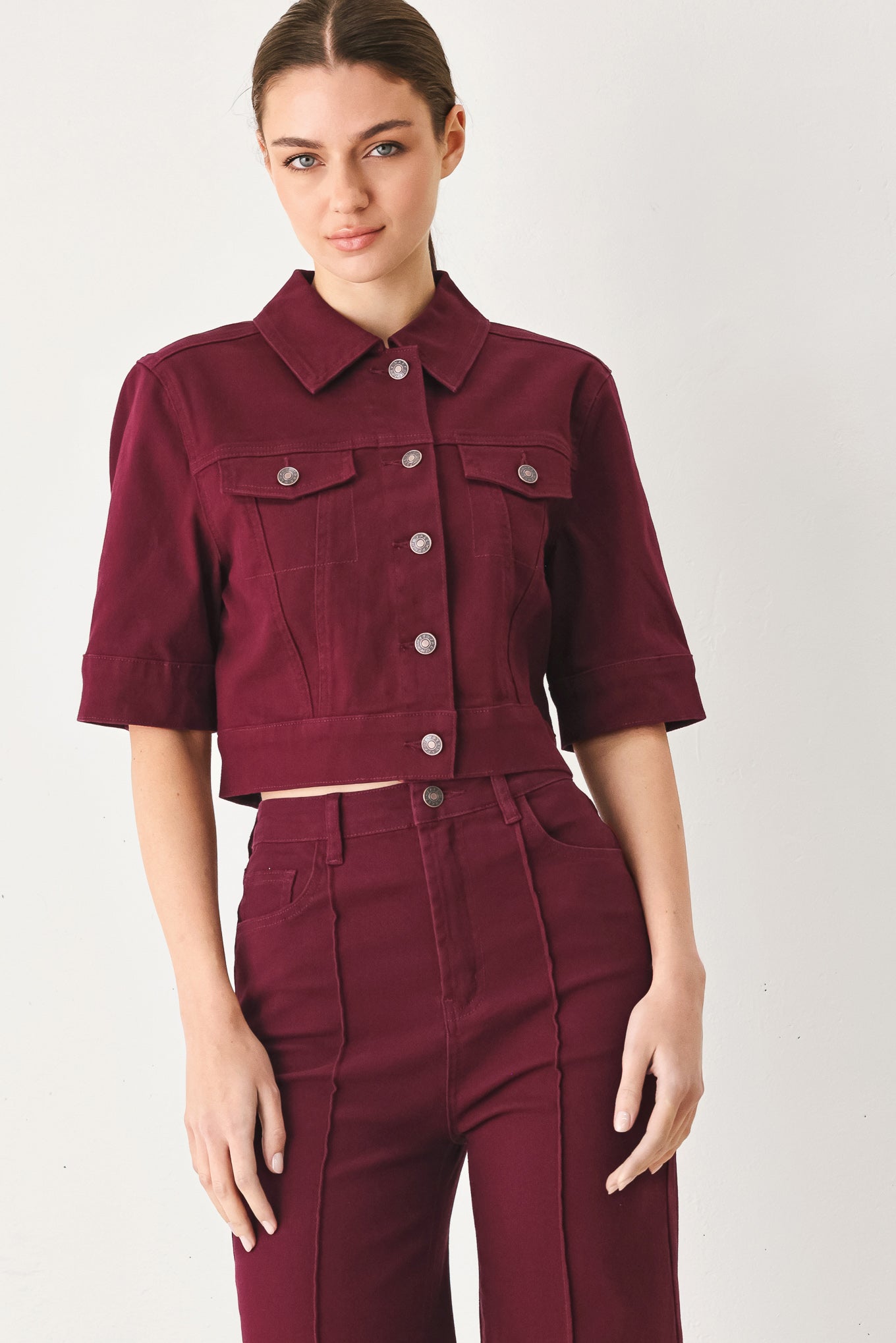 Woman wearing a burgundy short sleeve twill jacket with front button closure | FREEMARKET