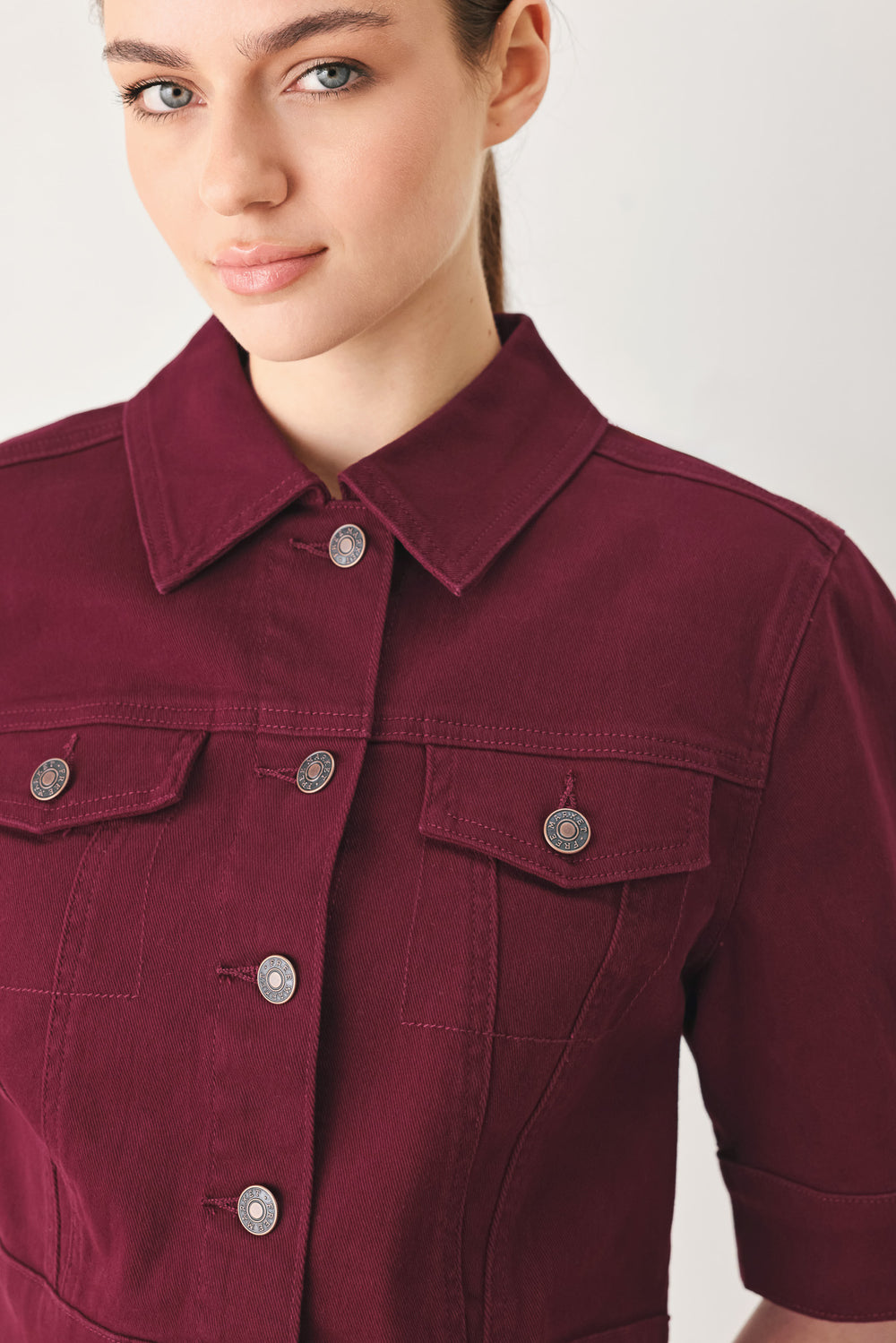 Woman wearing a burgundy short sleeve twill jacket with front button closure | FREEMARKET