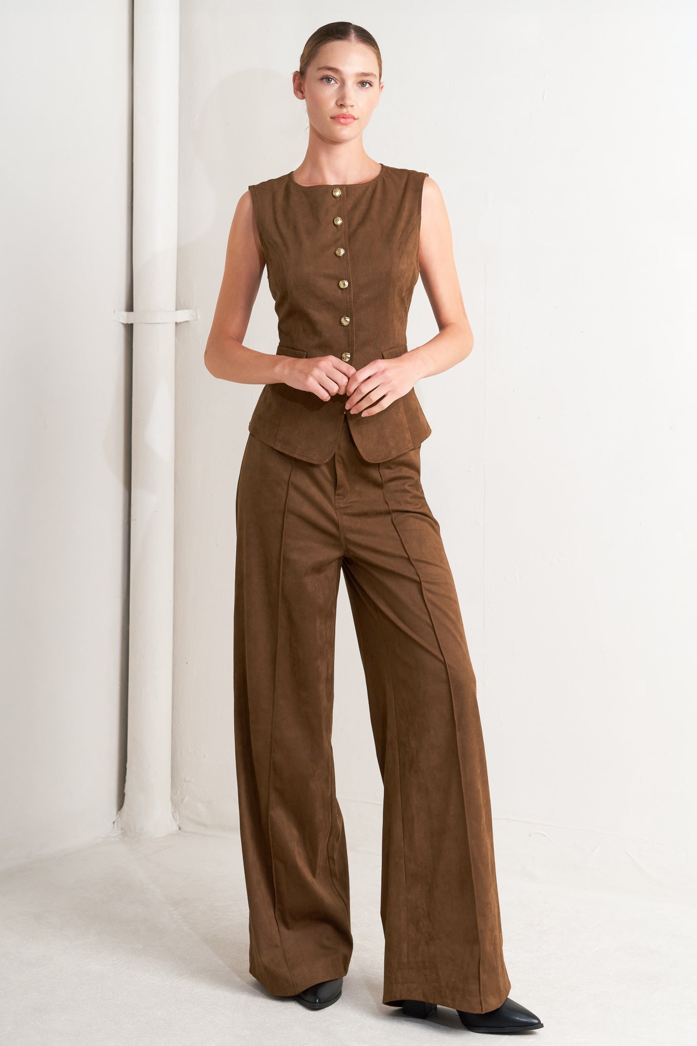A faux suede vest featuring round neckline, sleeveless, front button closure and side pocket.