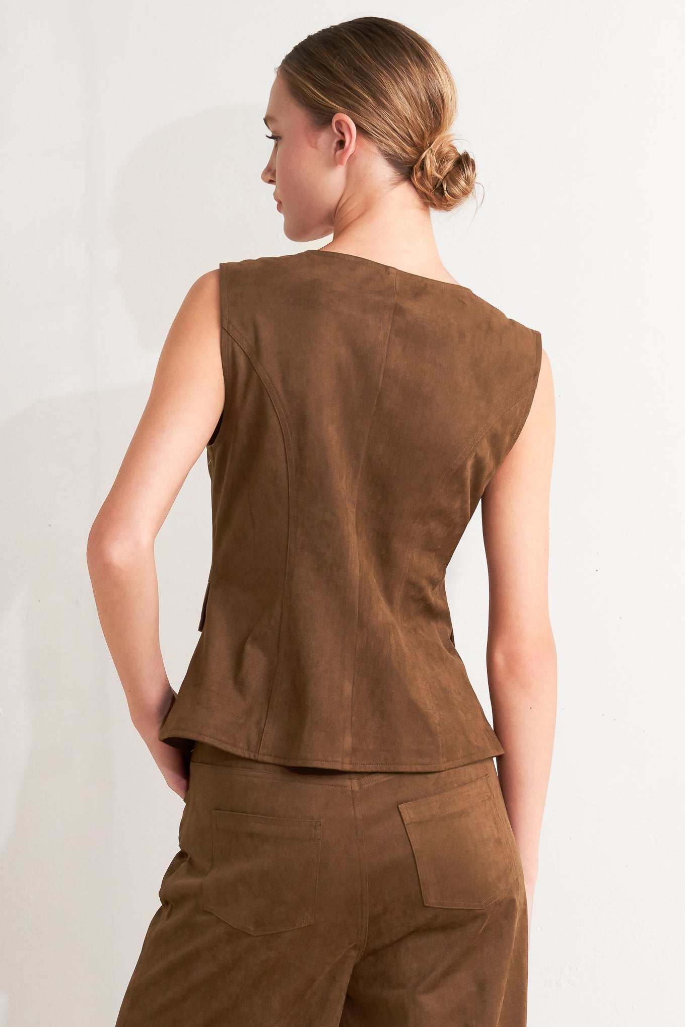 A faux suede vest featuring round neckline, sleeveless, front button closure and side pocket.