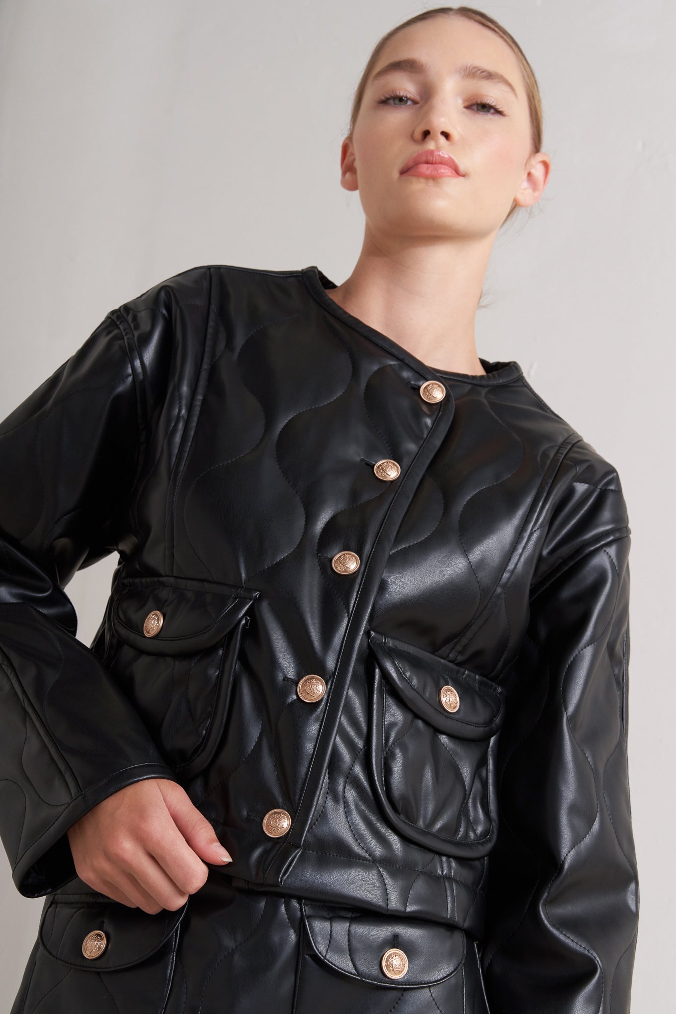 A quilted faux leather jacket with front pockets and button down closure.