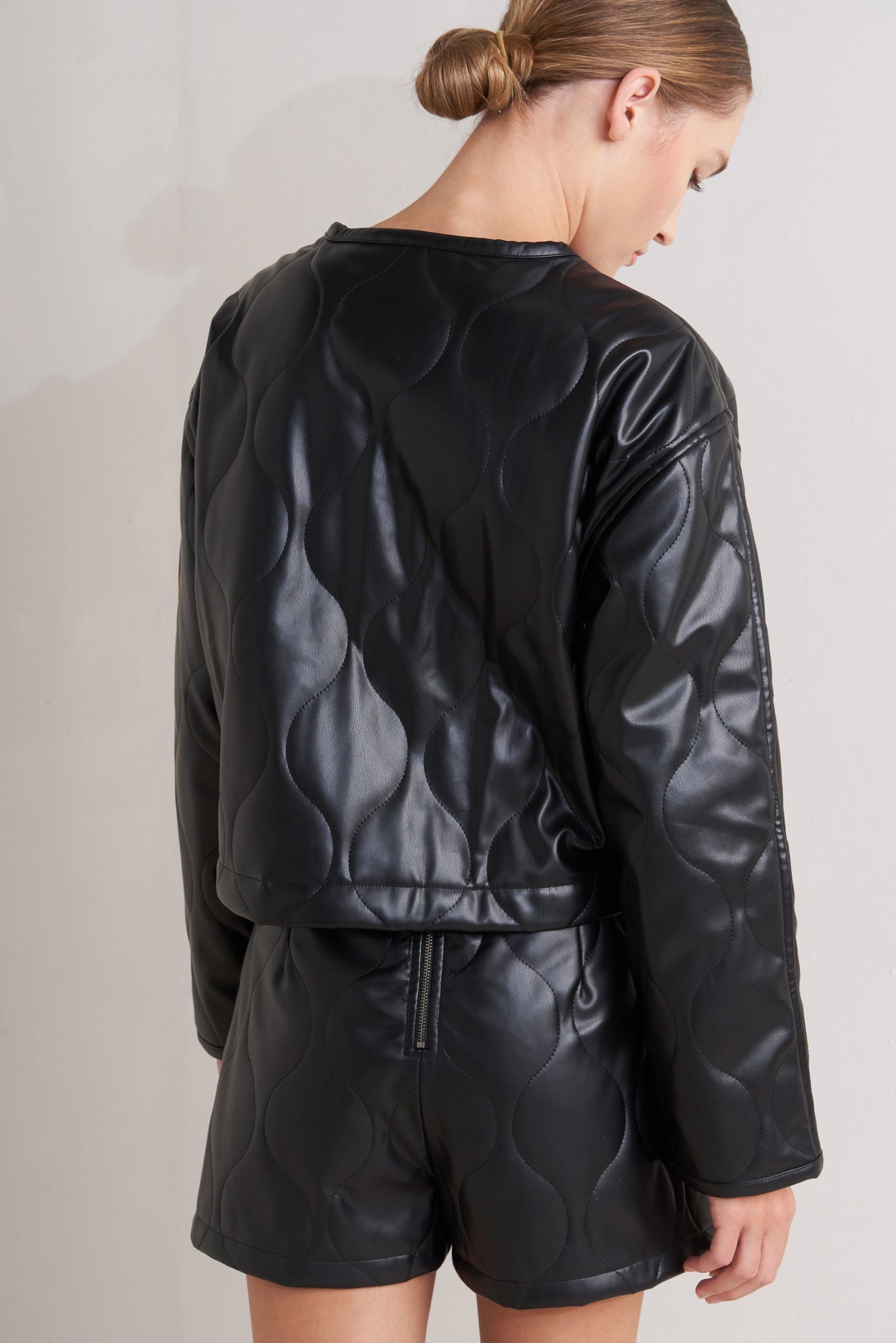 A quilted faux leather jacket with front pockets and button down closure.