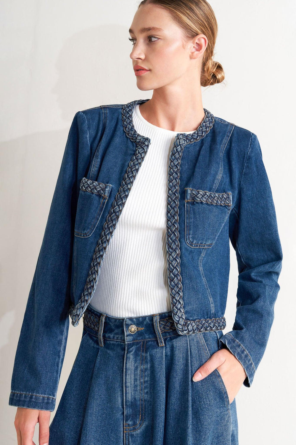A washed denim jacket featuring round neckline, braided trim and hook &amp; eye closure