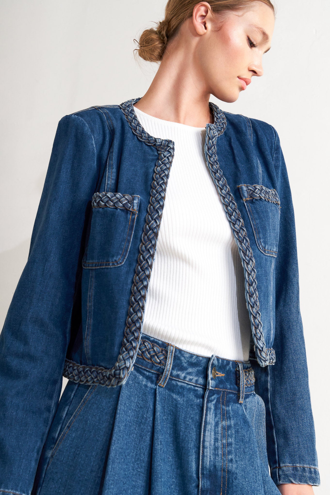 A washed denim jacket featuring round neckline, braided trim and hook &amp; eye closure