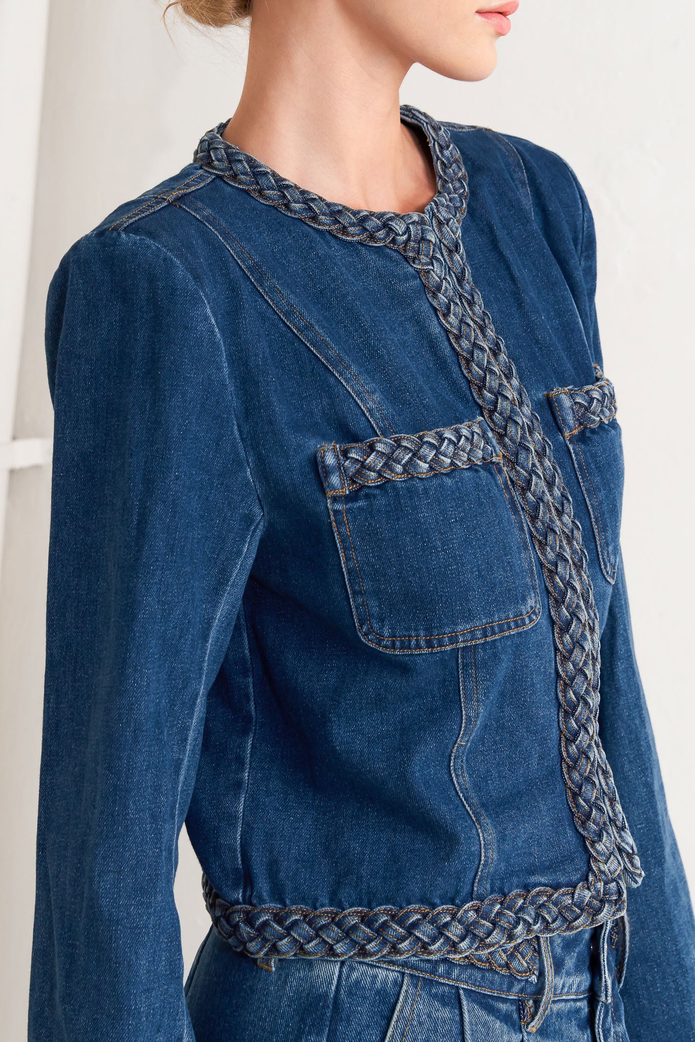 A washed denim jacket featuring round neckline, braided trim and hook &amp; eye closure