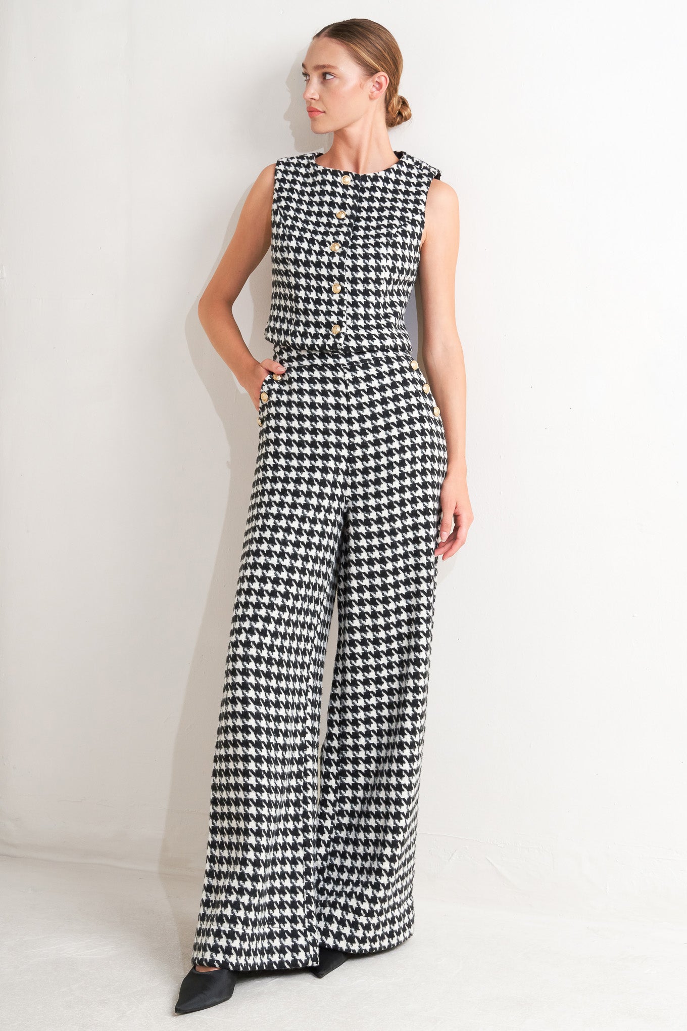 A woven houndstooth vest featuring round neckline, sleeveless and front button down.
