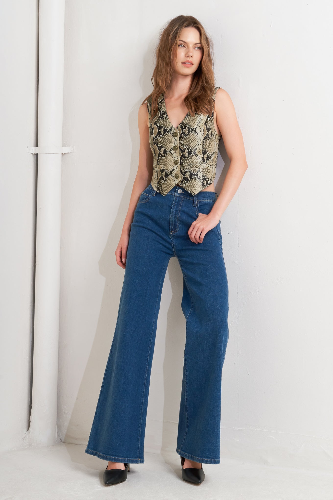 A snake-printed cropped faux leather vest with front button closure.