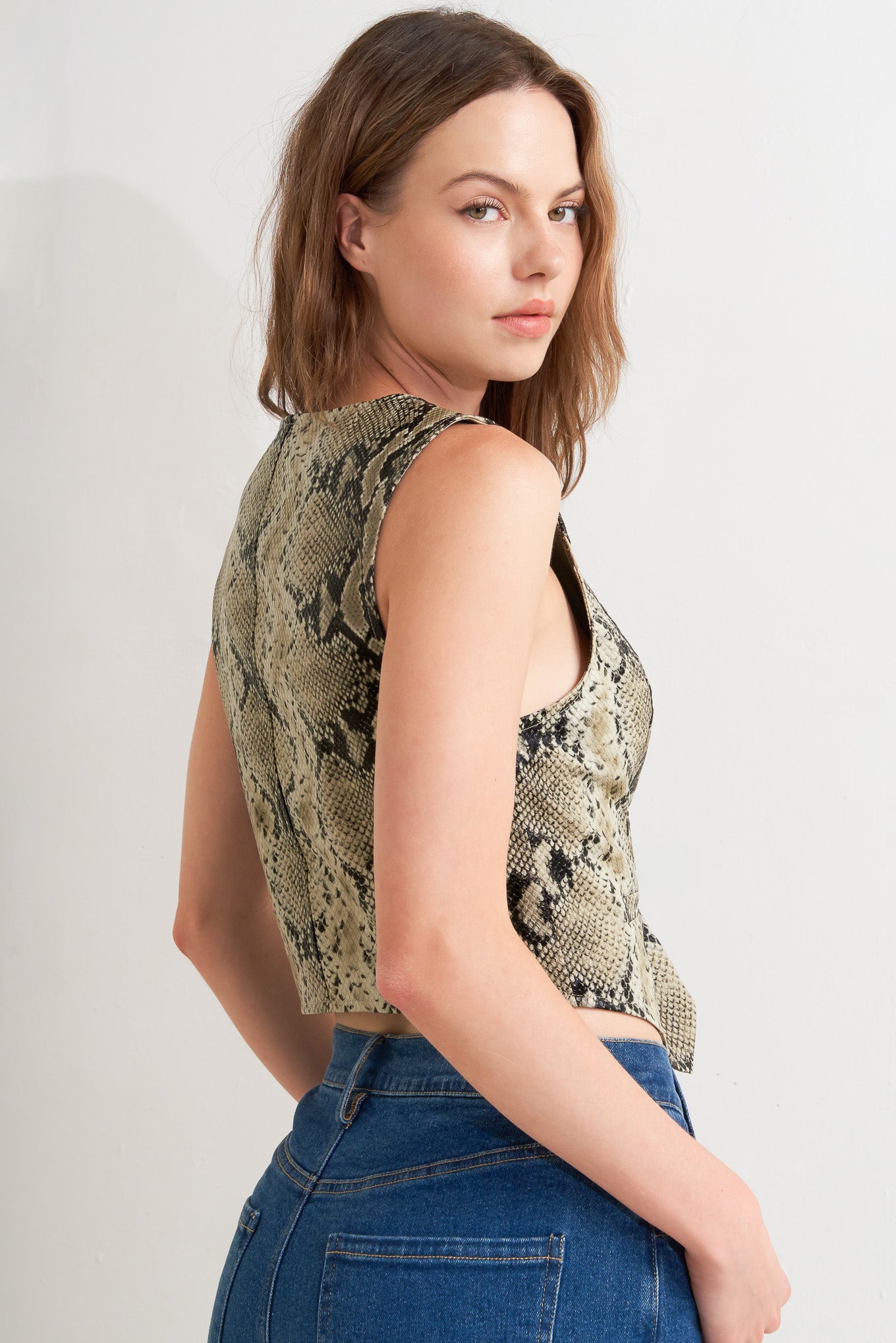A snake-printed cropped faux leather vest with front button closure.
