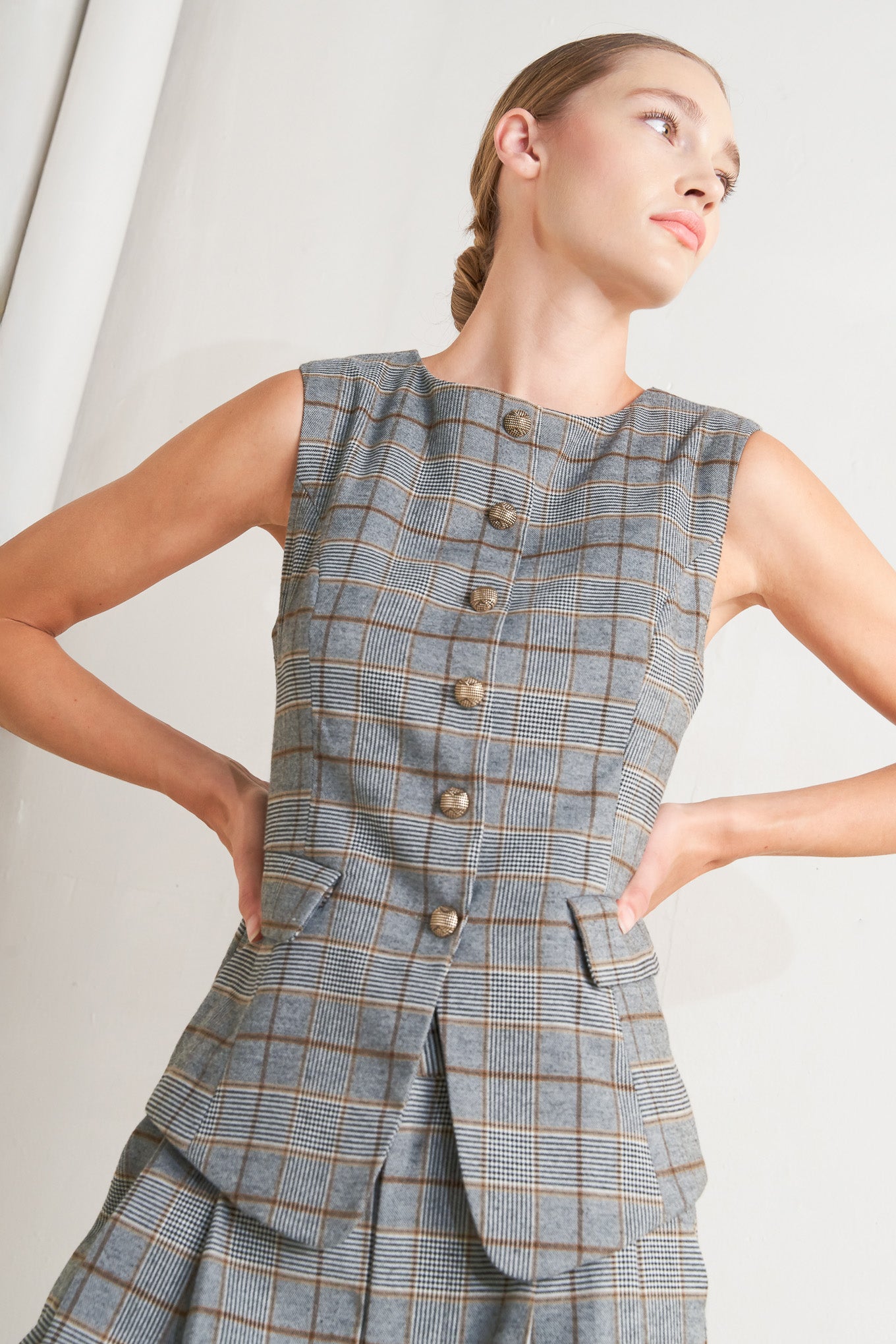 A plaid woven vest featuring round neckline, sleeveless, front button down and side pocket. 