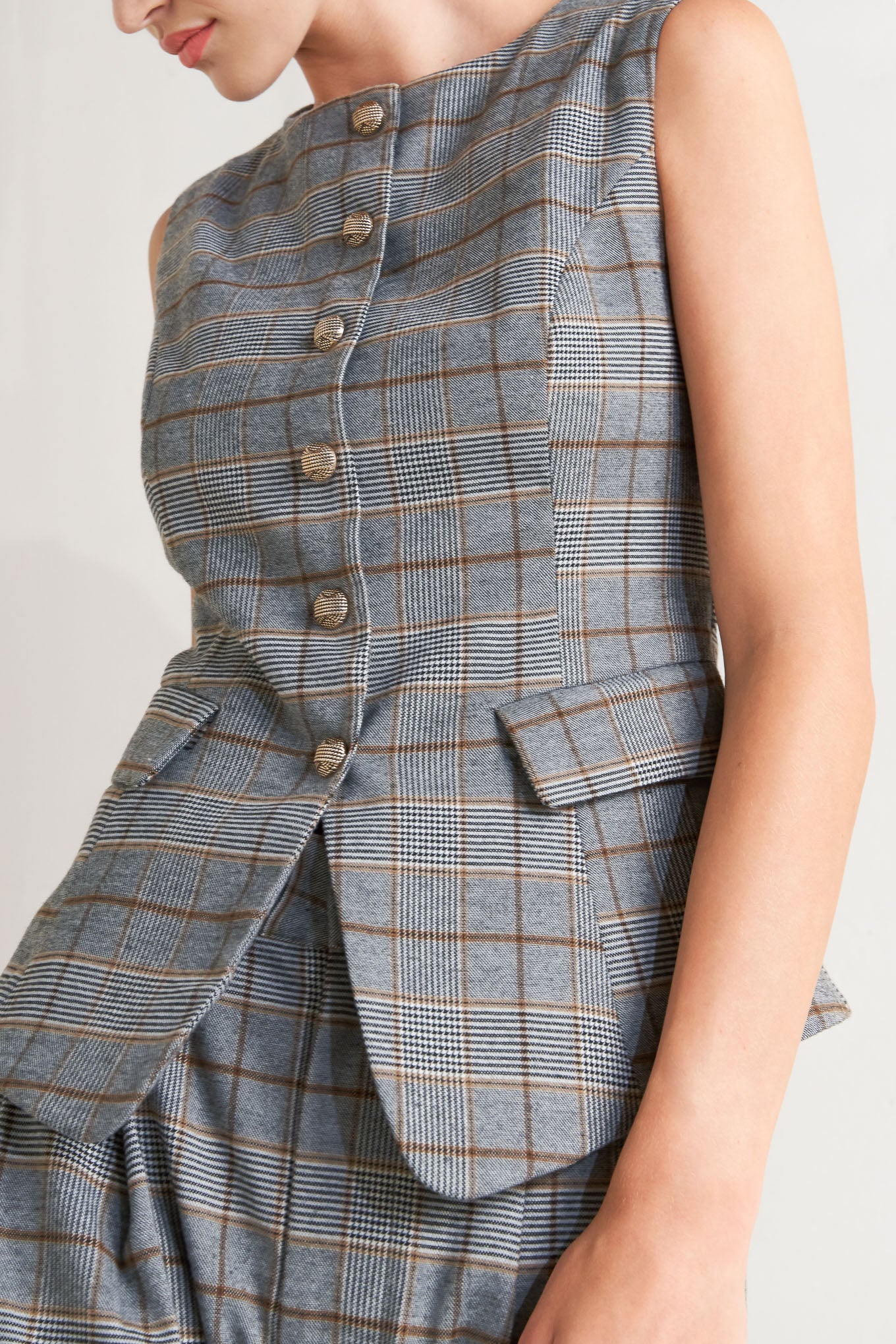 A plaid woven vest featuring round neckline, sleeveless, front button down and side pocket. 