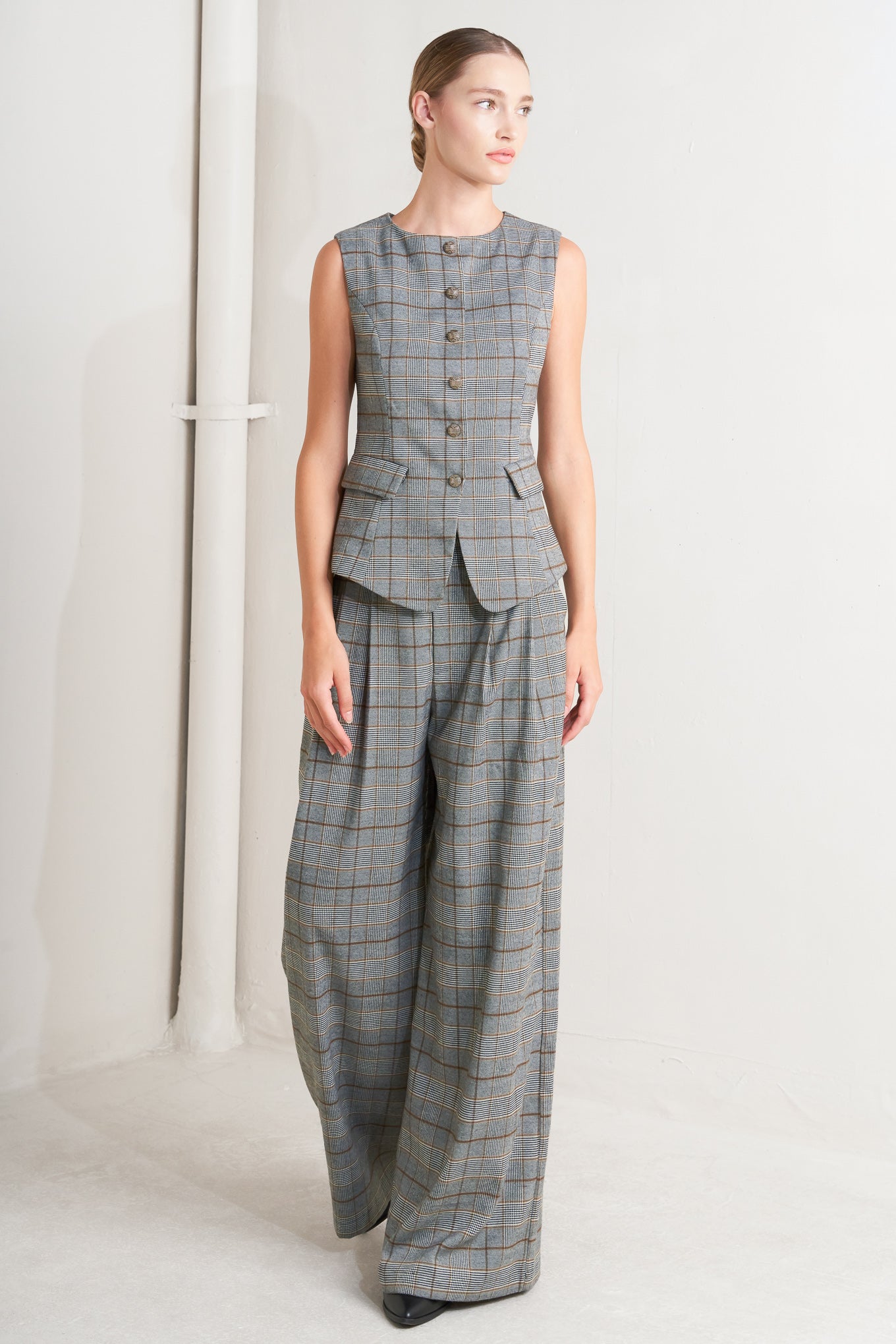 A plaid woven vest featuring round neckline, sleeveless, front button down and side pocket. 