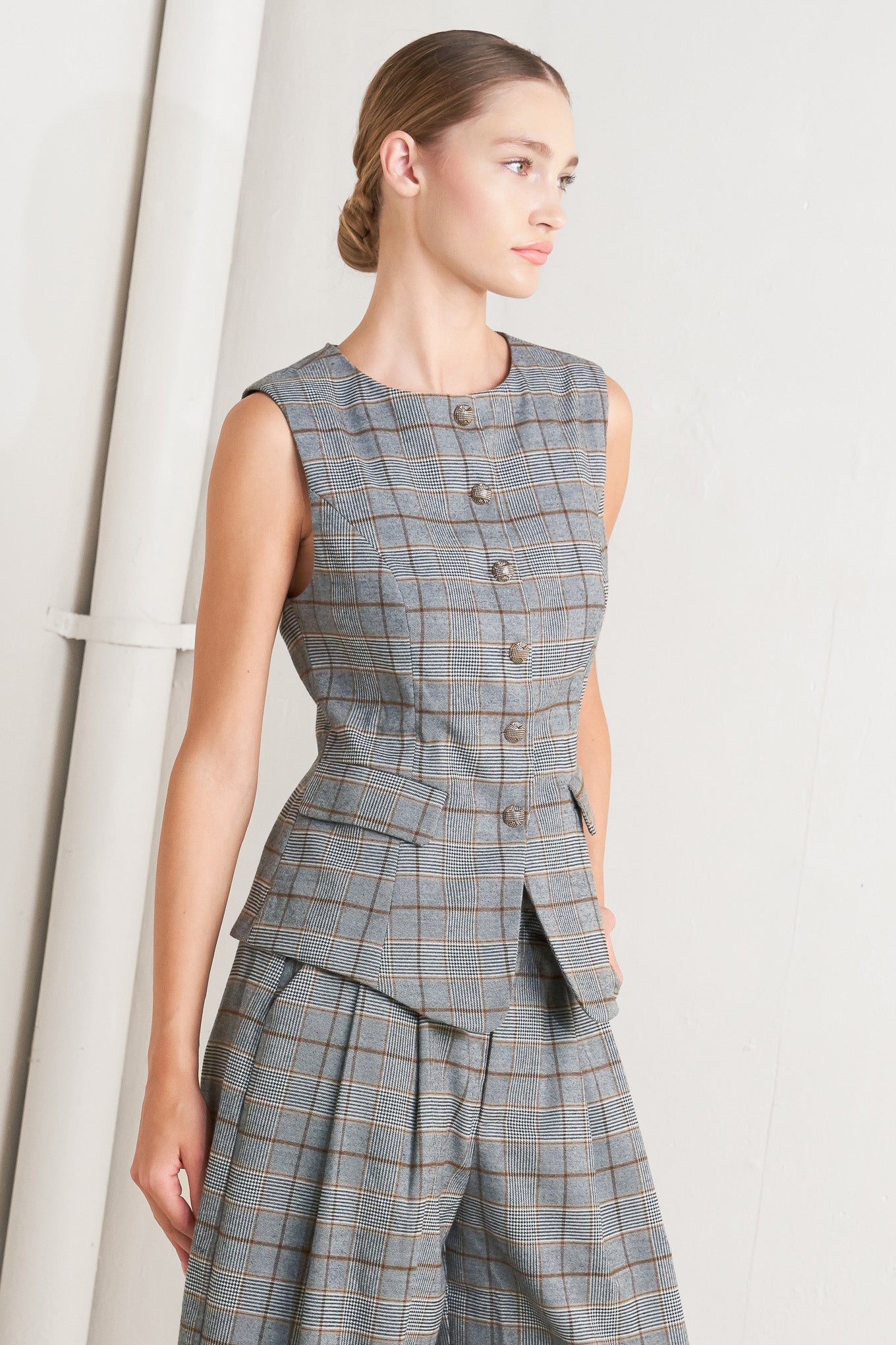 A plaid woven vest featuring round neckline, sleeveless, front button down and side pocket. 