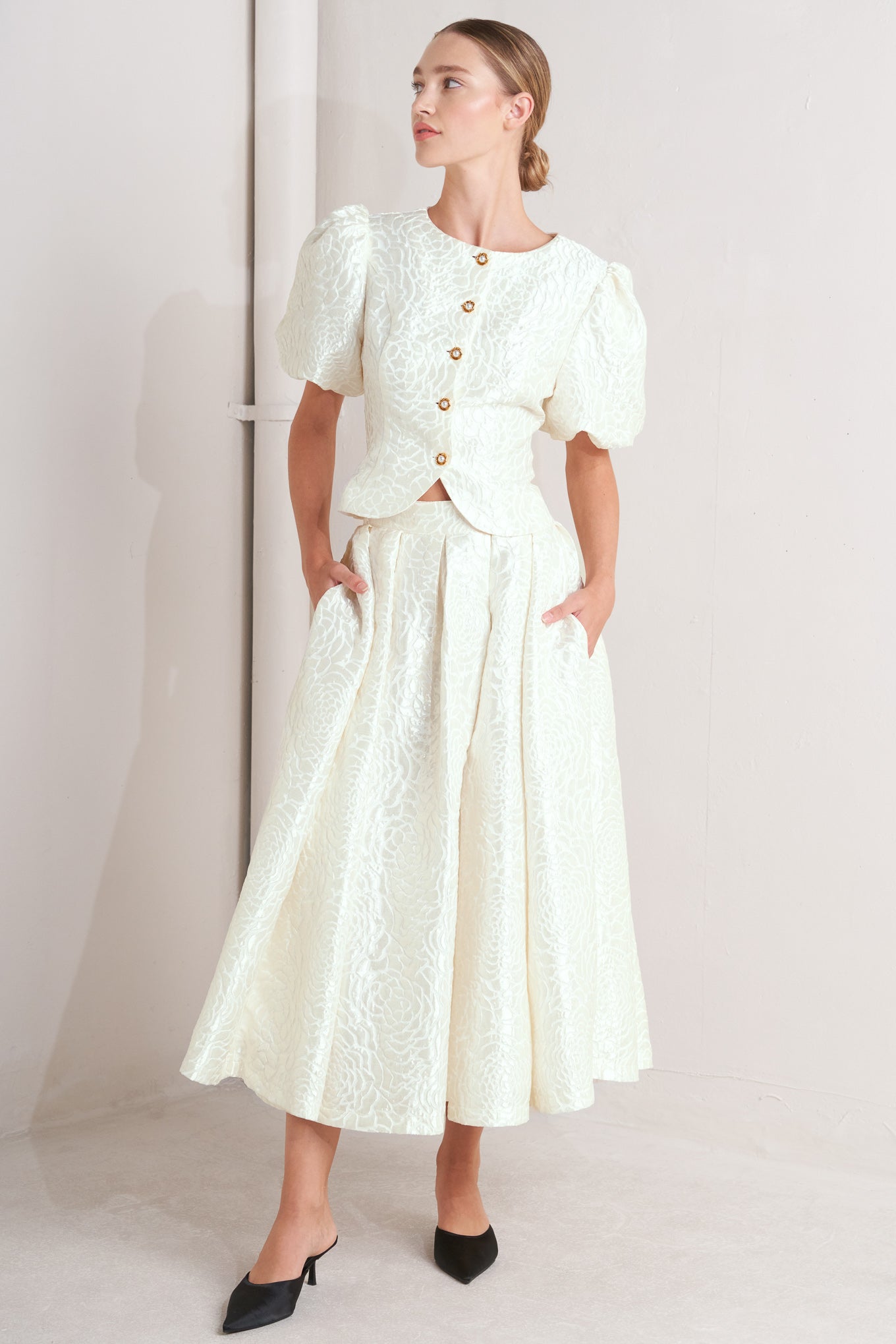 A textured woven top featuring round neckline, short puff sleeve and front button down.