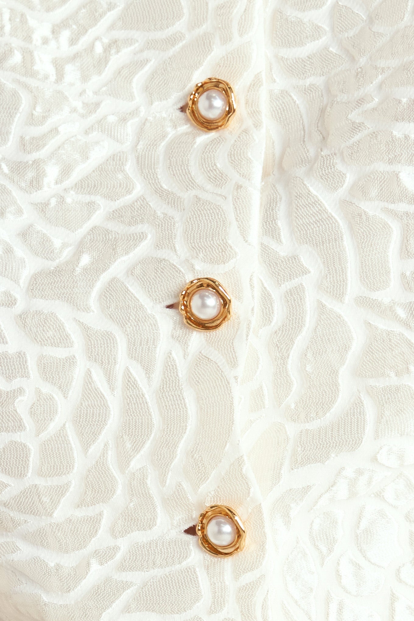 A textured woven top featuring round neckline, short puff sleeve and front button down.
