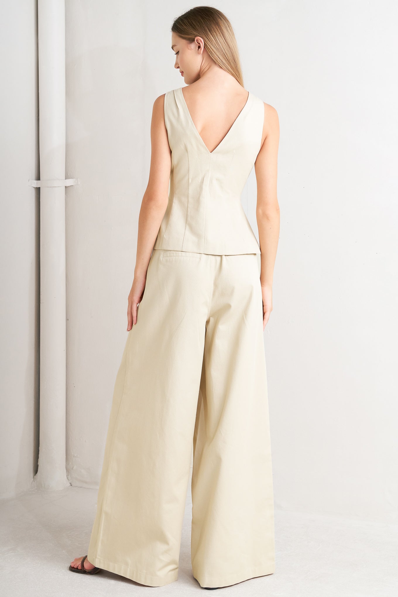 A solid woven vest featuring V neckline, sleeveless, front button down and V back.