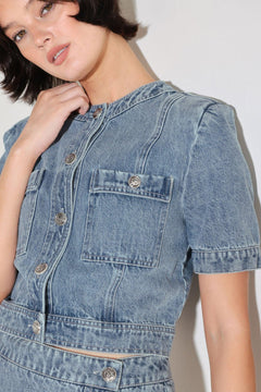 
A washed denim jacket featuring round neckline, short sleeve, front pockets and front button down. Matching skort FP2018T

Details:

Self : 100% Cotton

Size &amp; Fit

- Model is 5`8" And Wearing Size Small
- Measurements Taken From Size Small
- Approx. Length: 19"