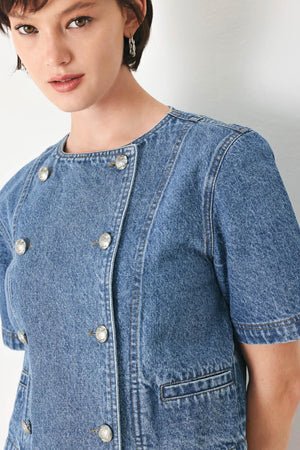 A washed denim jacket featuring round neckline, elbow sleeve, double button down and side pocket.