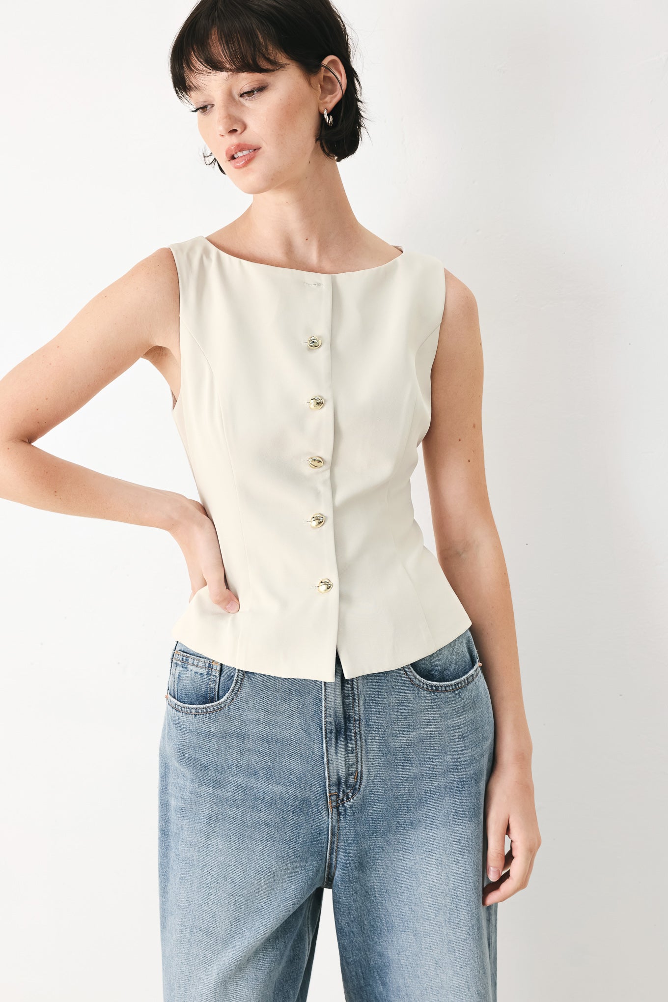Woman wearing an ivory woven vest with wide neckline, sleeveless and front button down| FREEMARKET