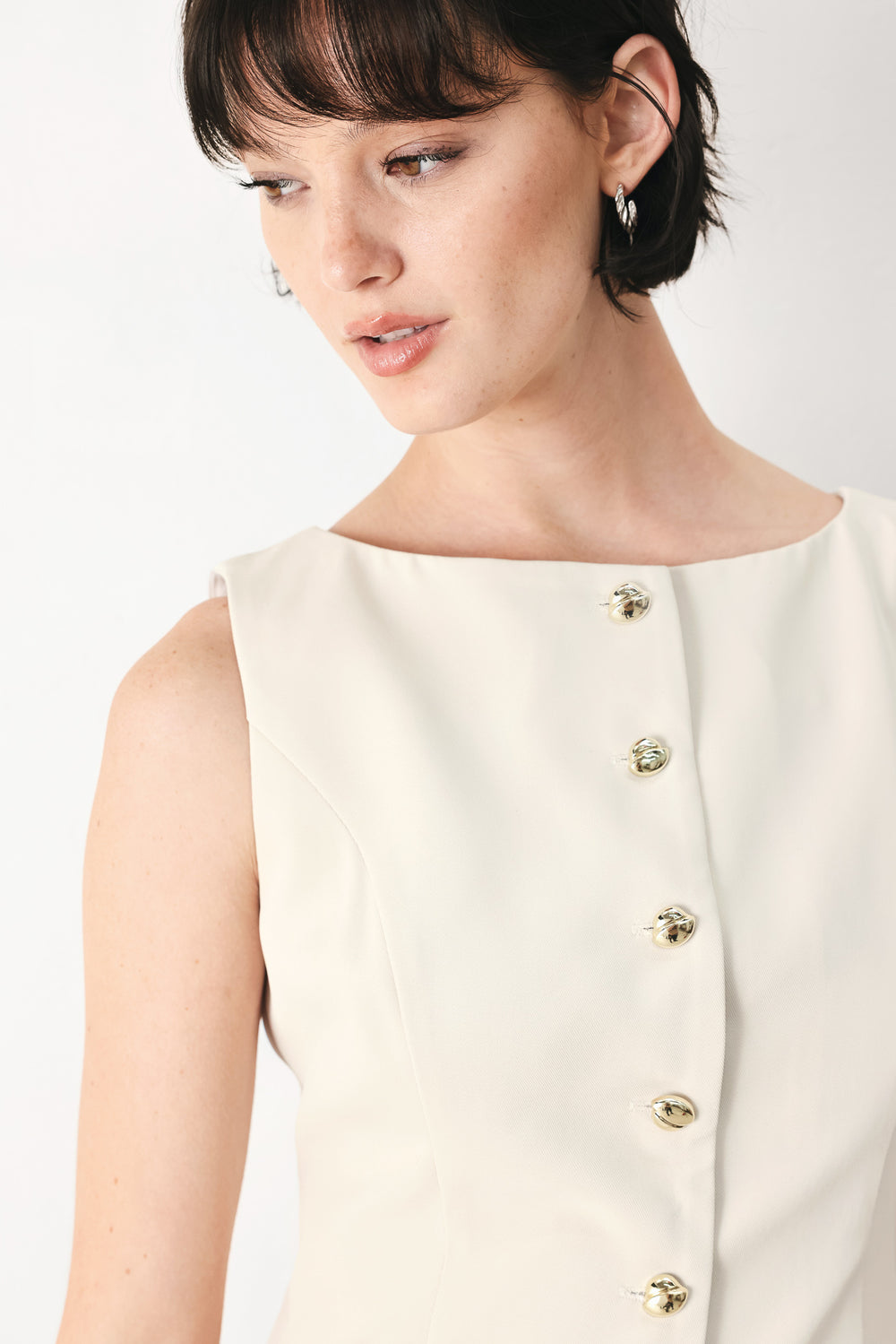 Woman wearing an ivory woven vest with wide neckline, sleeveless and front button down| FREEMARKET