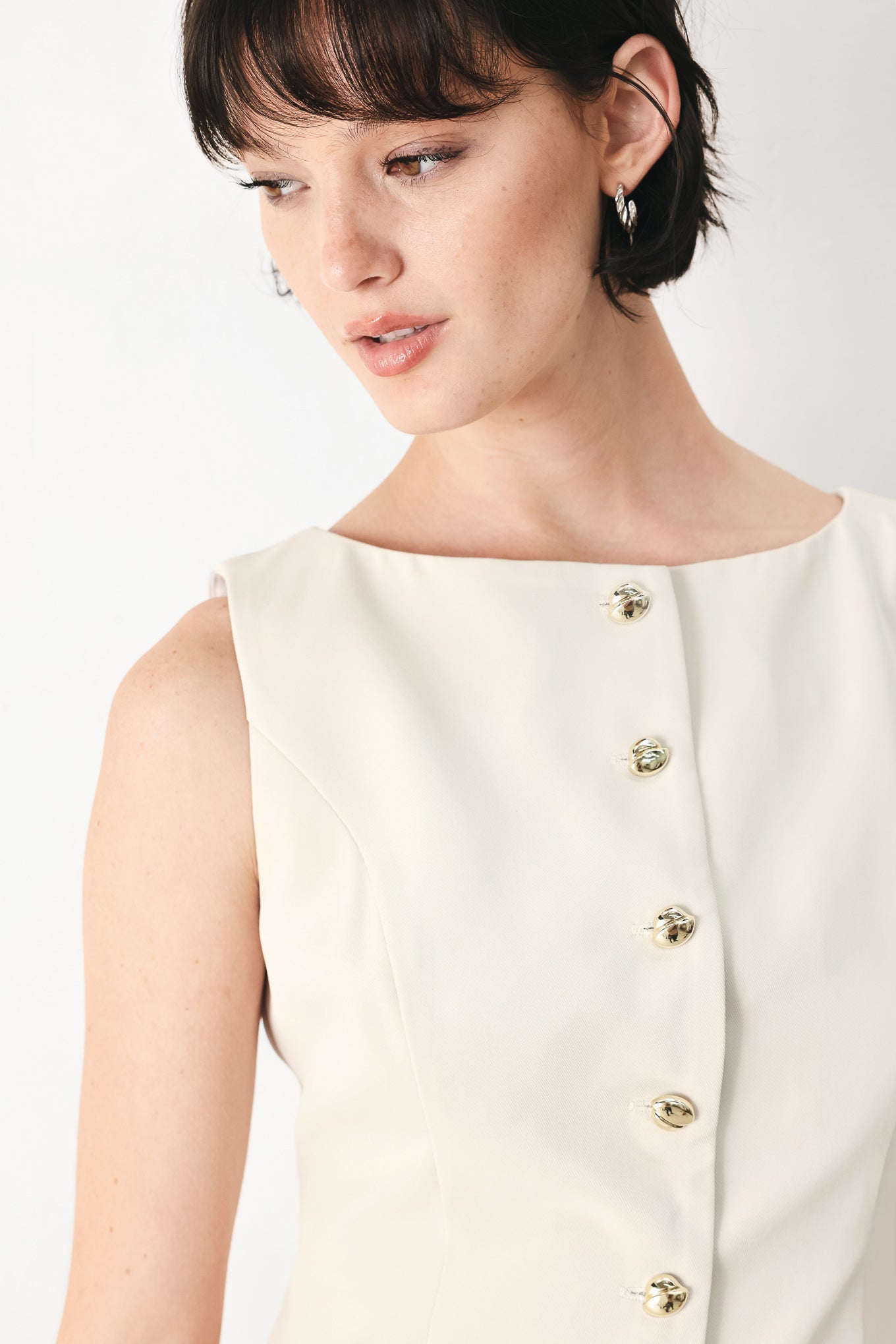 Woman wearing an ivory woven vest with wide neckline, sleeveless and front button down| FREEMARKET