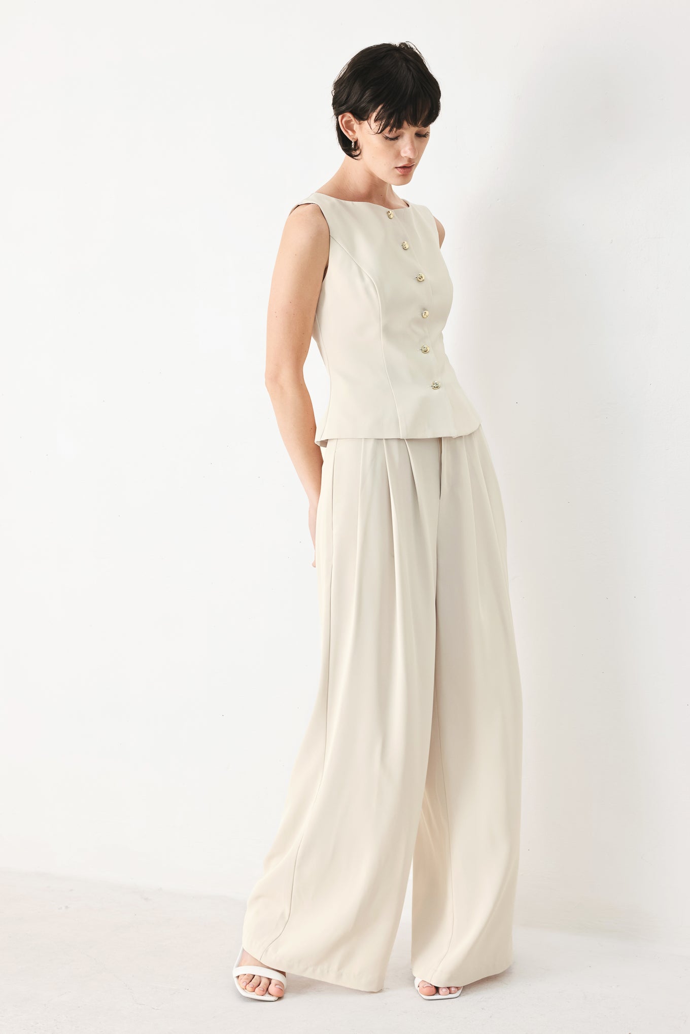 Woman wearing an ivory woven vest with wide neckline, sleeveless and front button down| FREEMARKET