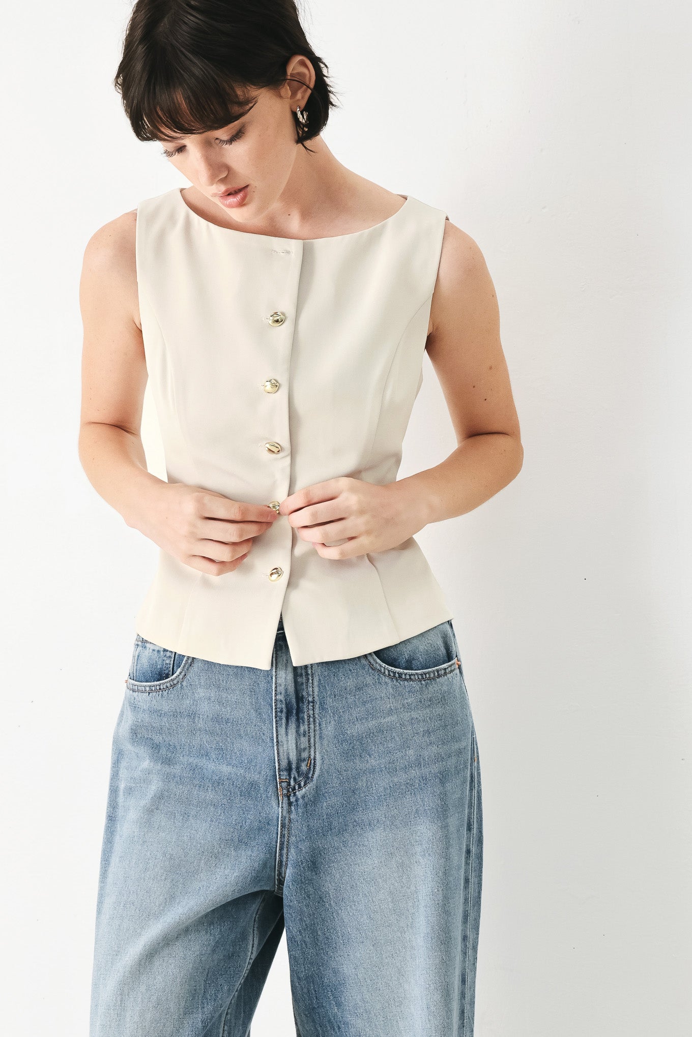 Woman wearing an ivory woven vest with wide neckline, sleeveless and front button down| FREEMARKET