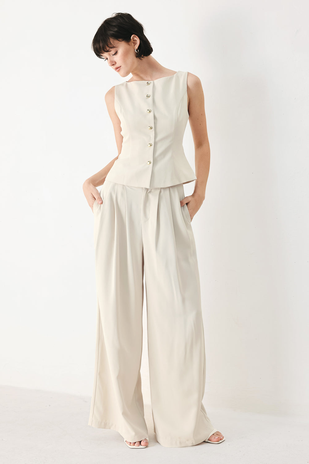 Woman wearing an ivory woven vest with wide neckline, sleeveless and front button down| FREEMARKET
