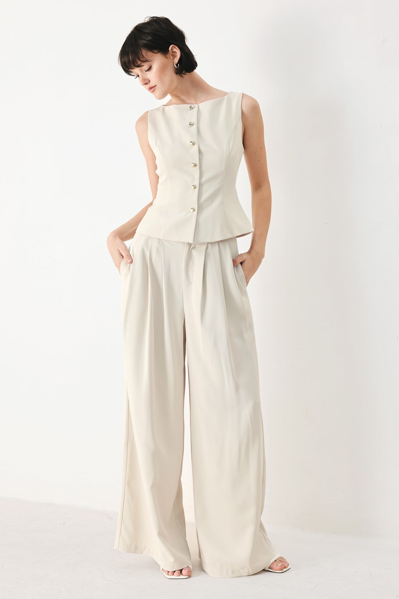 Woman wearing an ivory woven vest with wide neckline, sleeveless and front button down| FREEMARKET