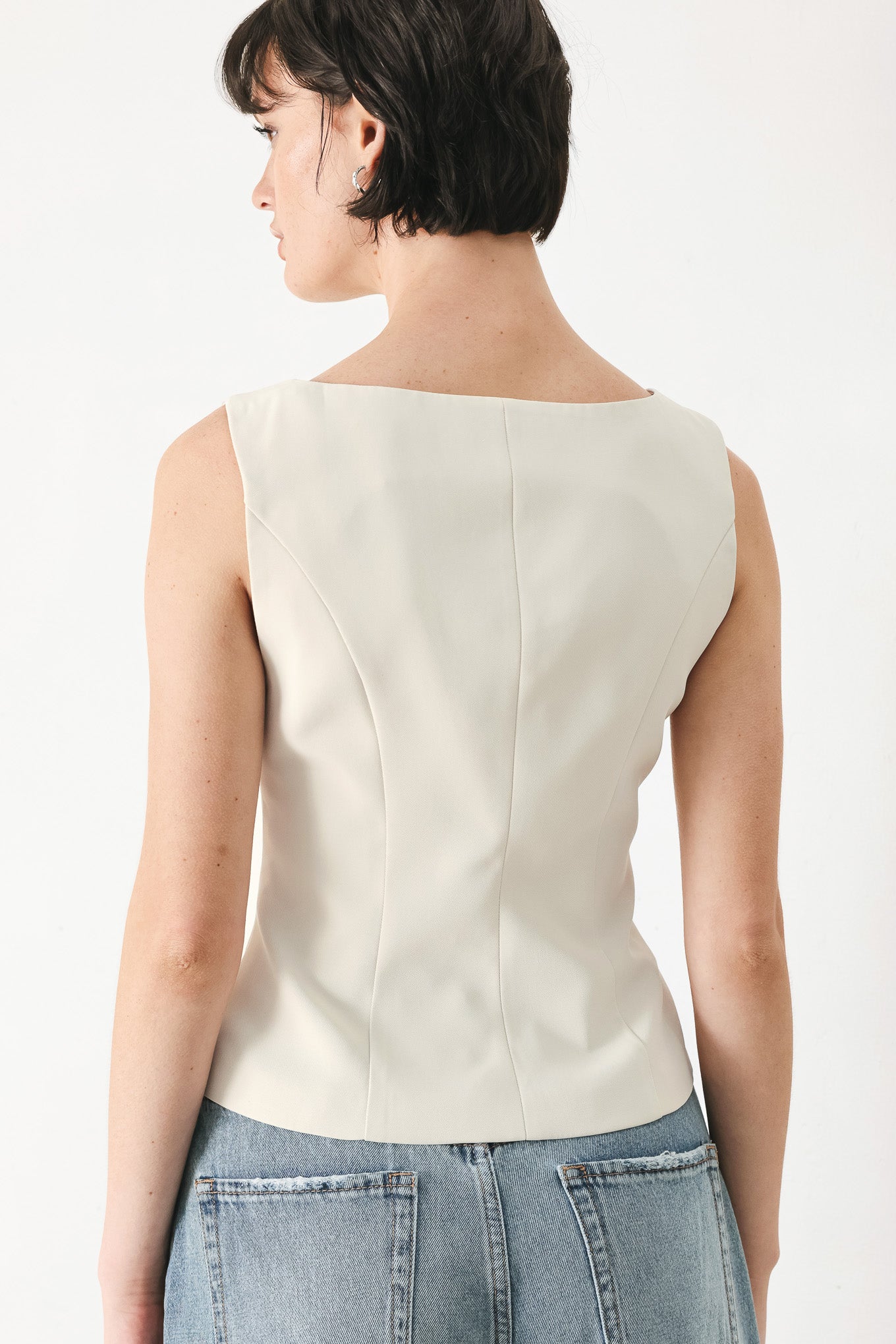 Woman wearing an ivory woven vest with wide neckline, sleeveless and front button down| FREEMARKET