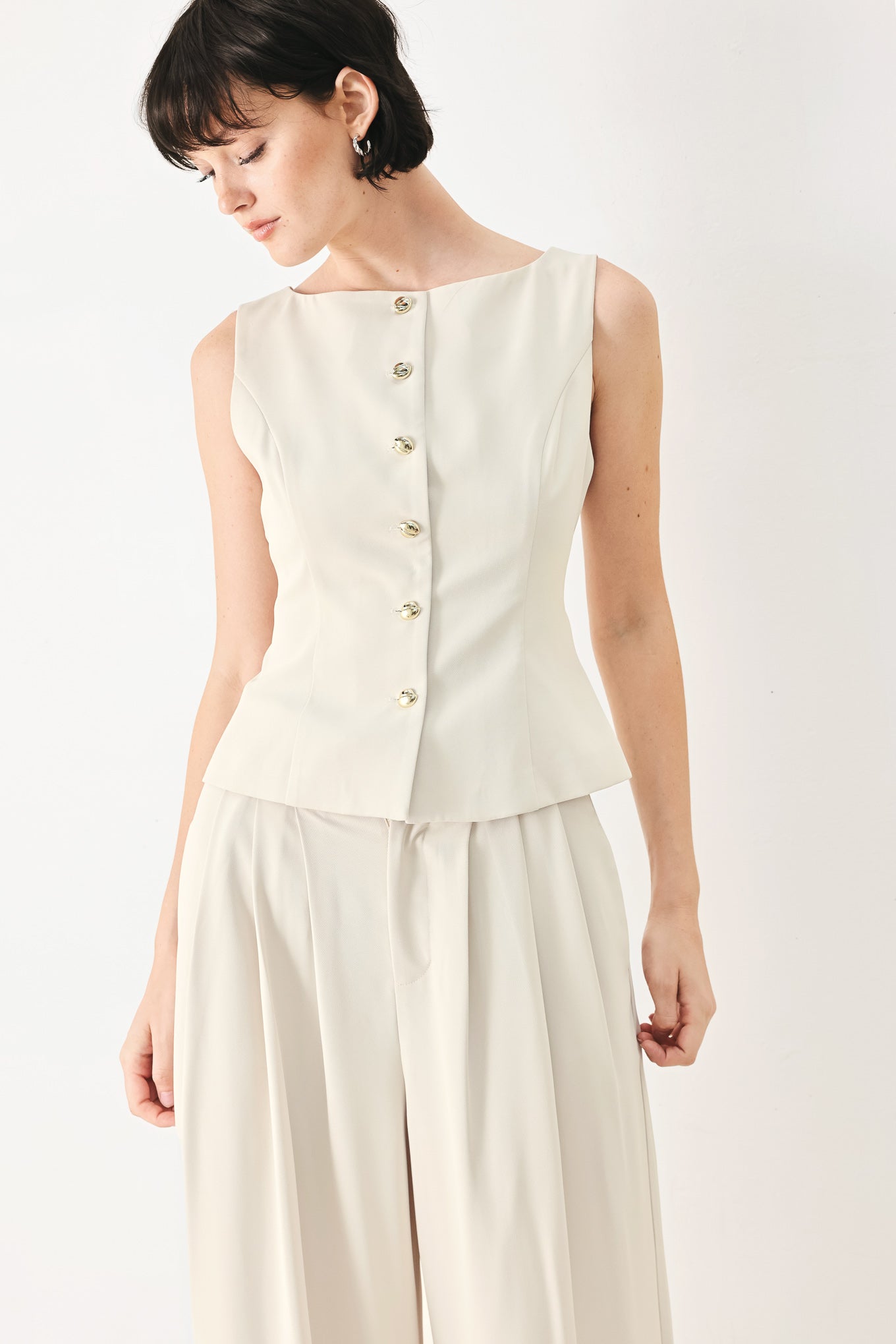 Woman wearing an ivory woven vest with wide neckline, sleeveless and front button down| FREEMARKET