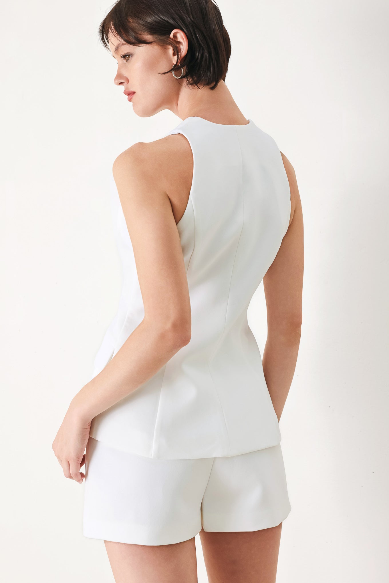 A solid woven vest featuring sweetheart neckline, button down and peplum.
