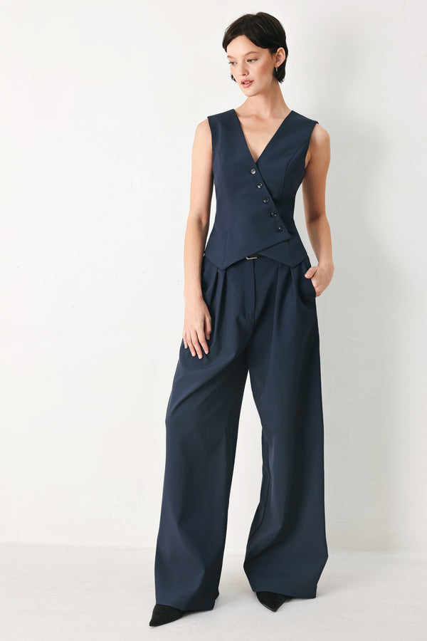 Woman wearing a navy blue sleeveless vest with asymmetrical overlap and buttons | FREEMARKET