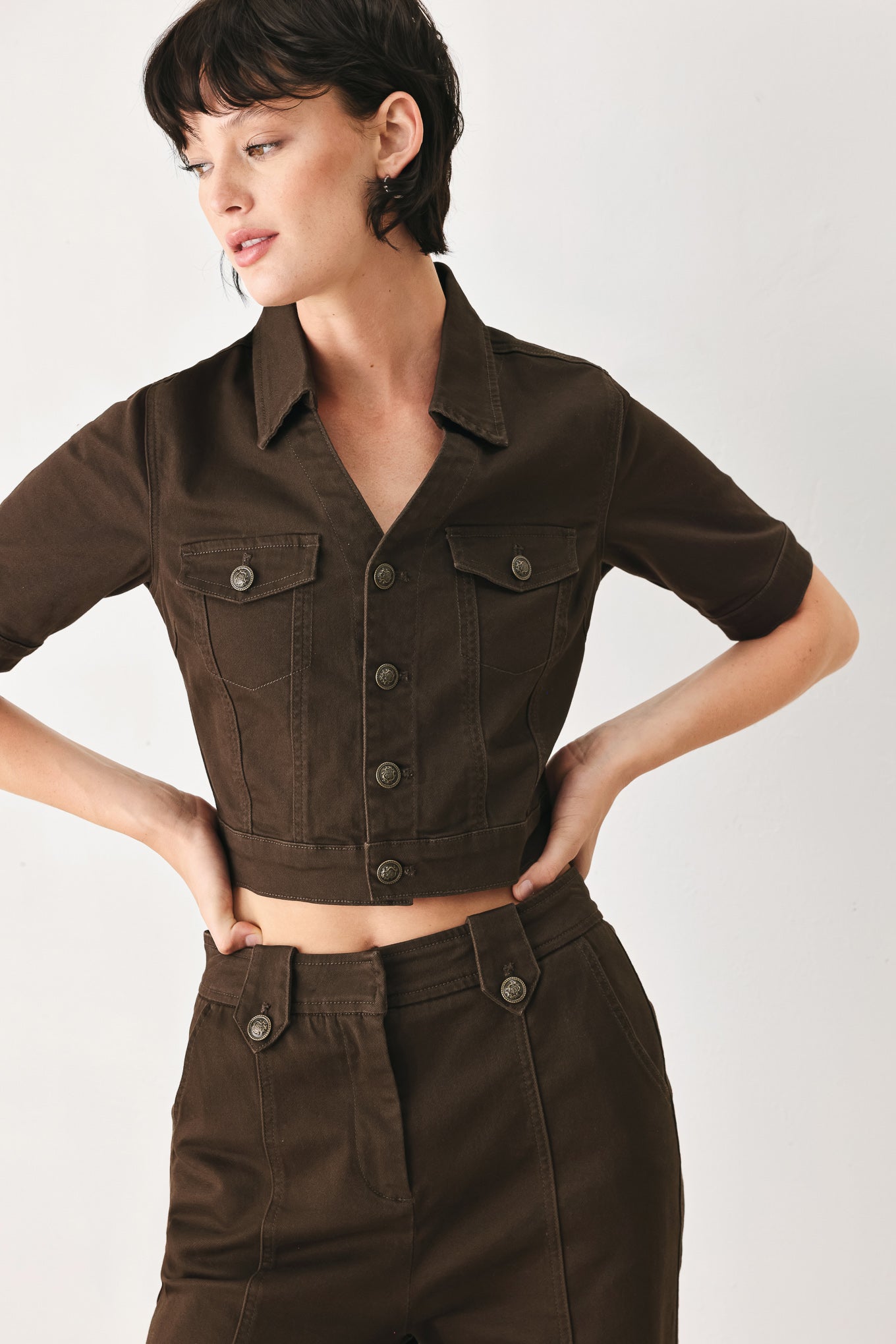Woman wearing a short sleeve brown denim jacket with collar, V neckline, and front button closure | FREEMARKET