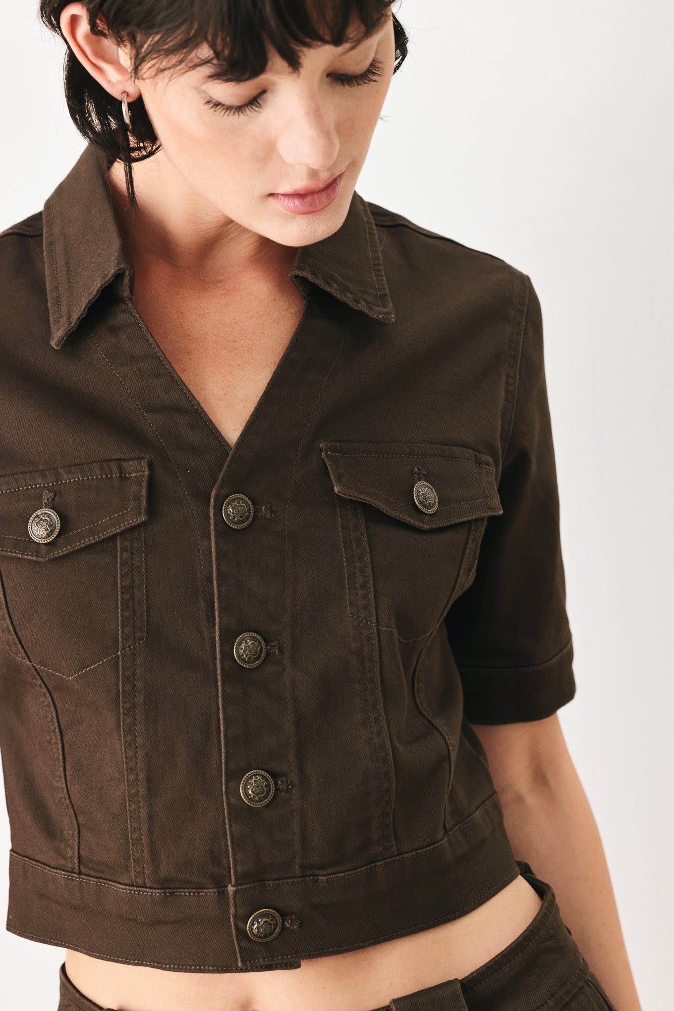 Woman wearing a short sleeve brown denim jacket with collar, V neckline, and front button closure | FREEMARKET