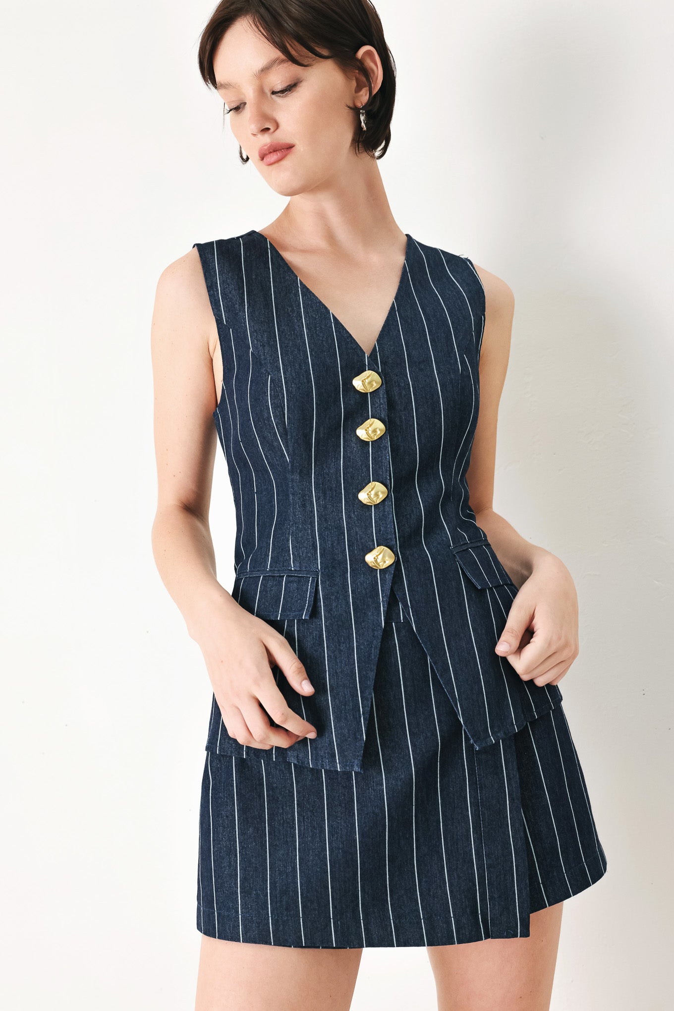 A striped woven vest with V neckline and front button down.