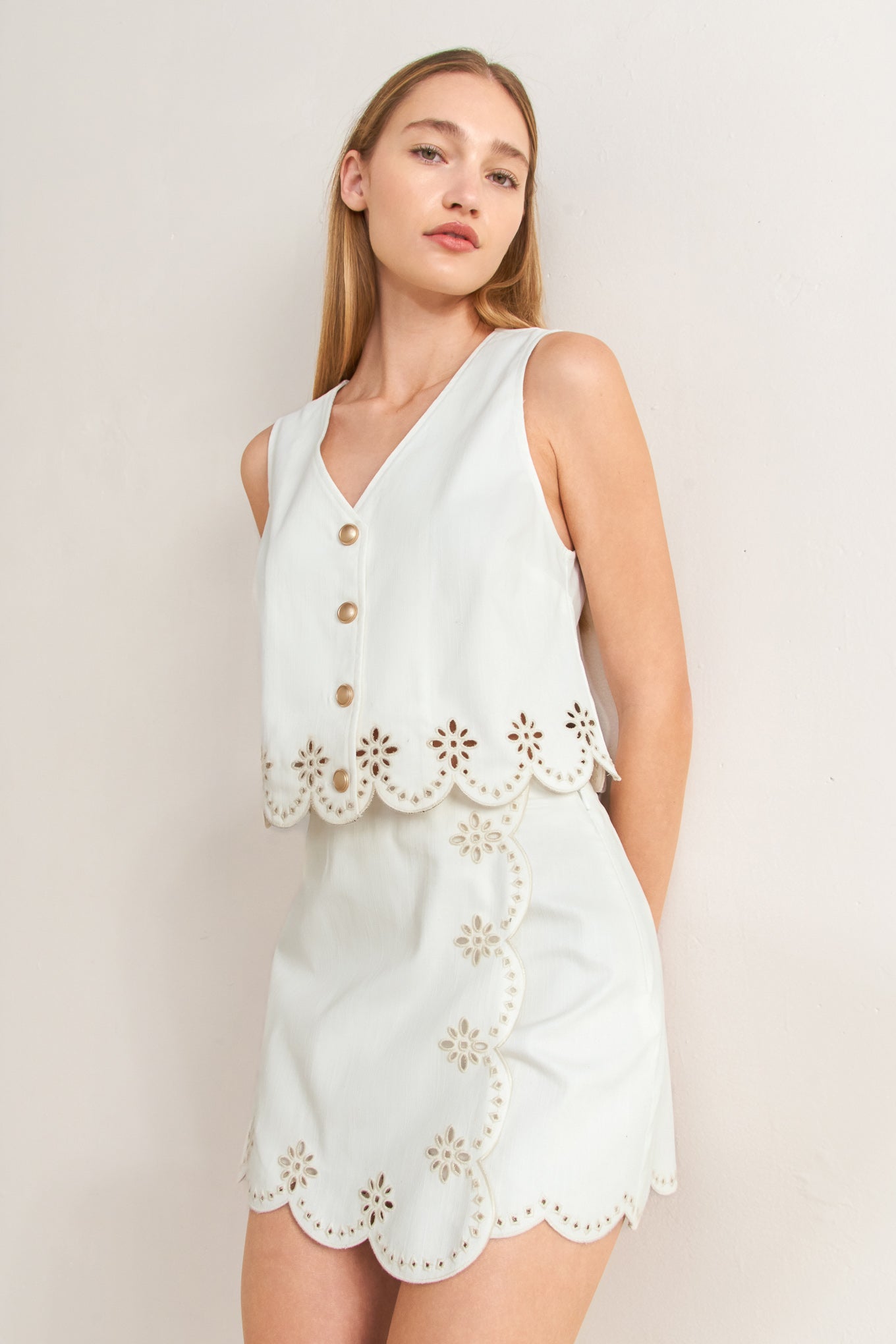 Woman wearing a light blue dress with floral cut-out details on a plain background