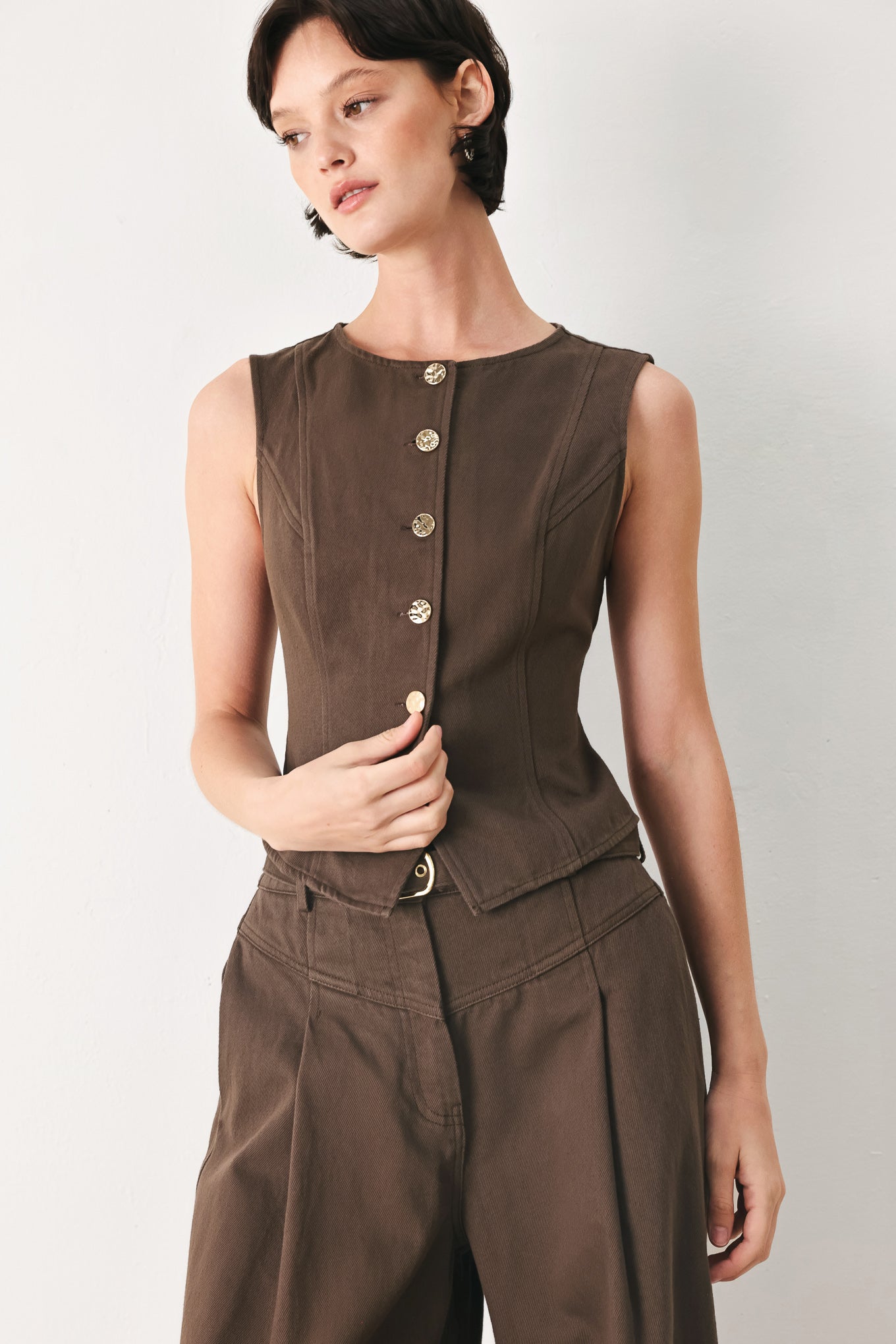 Woman wearing a brown sleeveless vest with round neckline, buttons and matching pants | FREEMARKET 