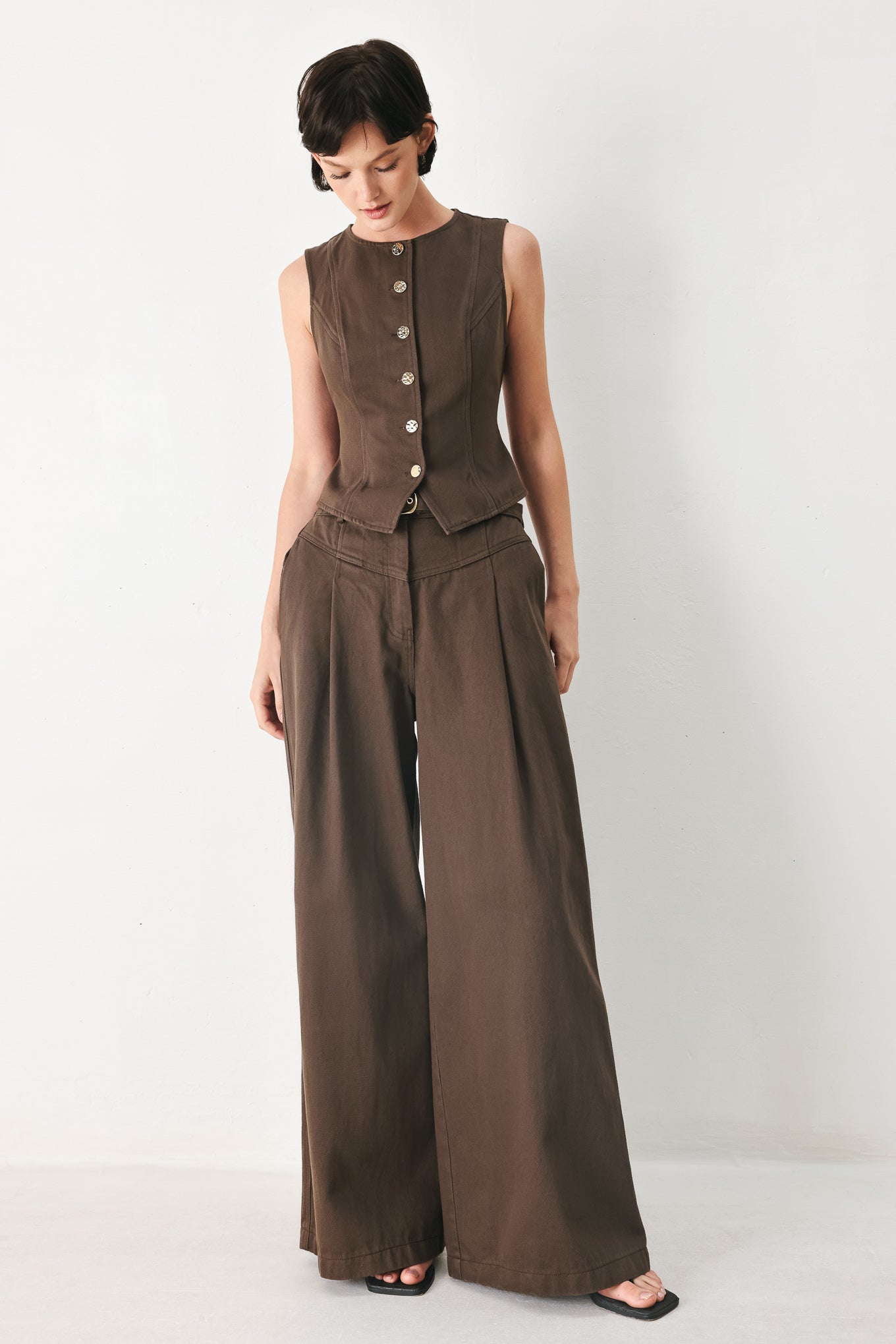 Woman wearing a brown sleeveless vest with round neckline, buttons and matching pants | FREEMARKET 