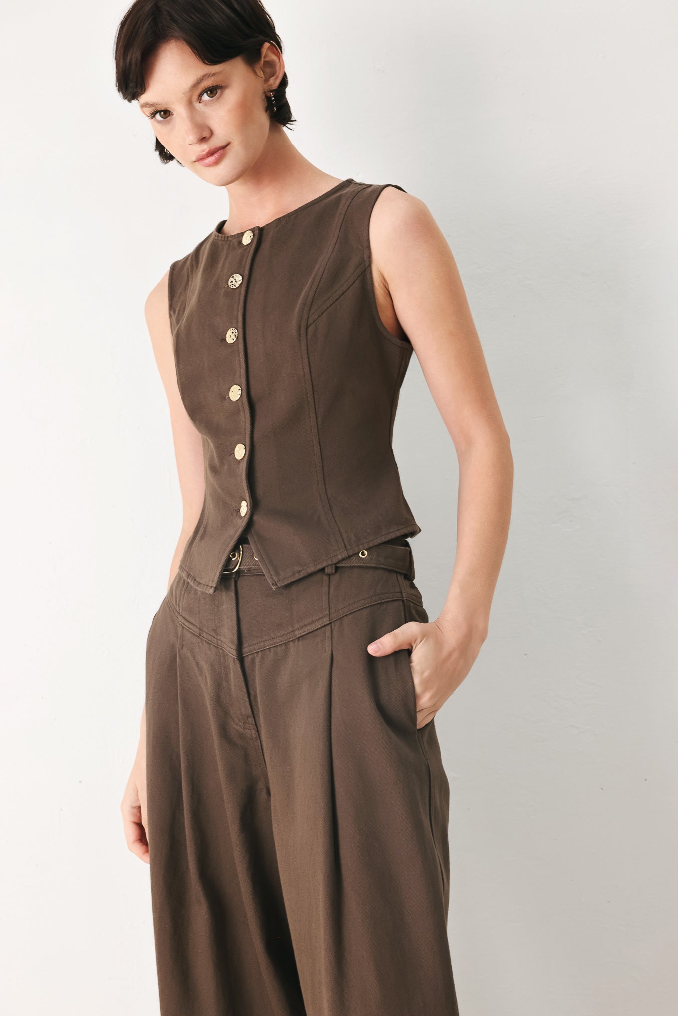 Woman wearing a brown sleeveless vest with round neckline, buttons and matching pants | FREEMARKET 