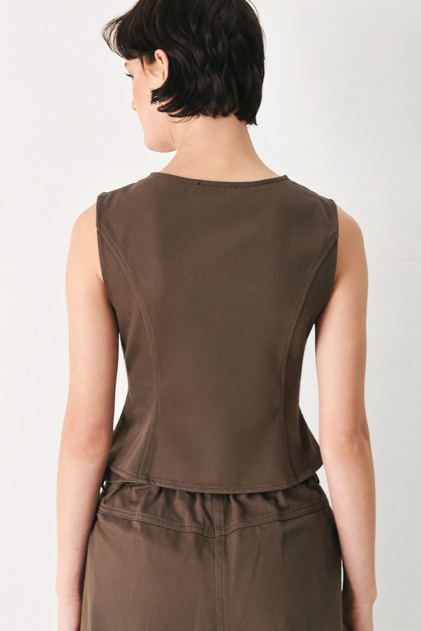 Woman wearing a brown sleeveless vest with round neckline, buttons and matching pants | FREEMARKET 