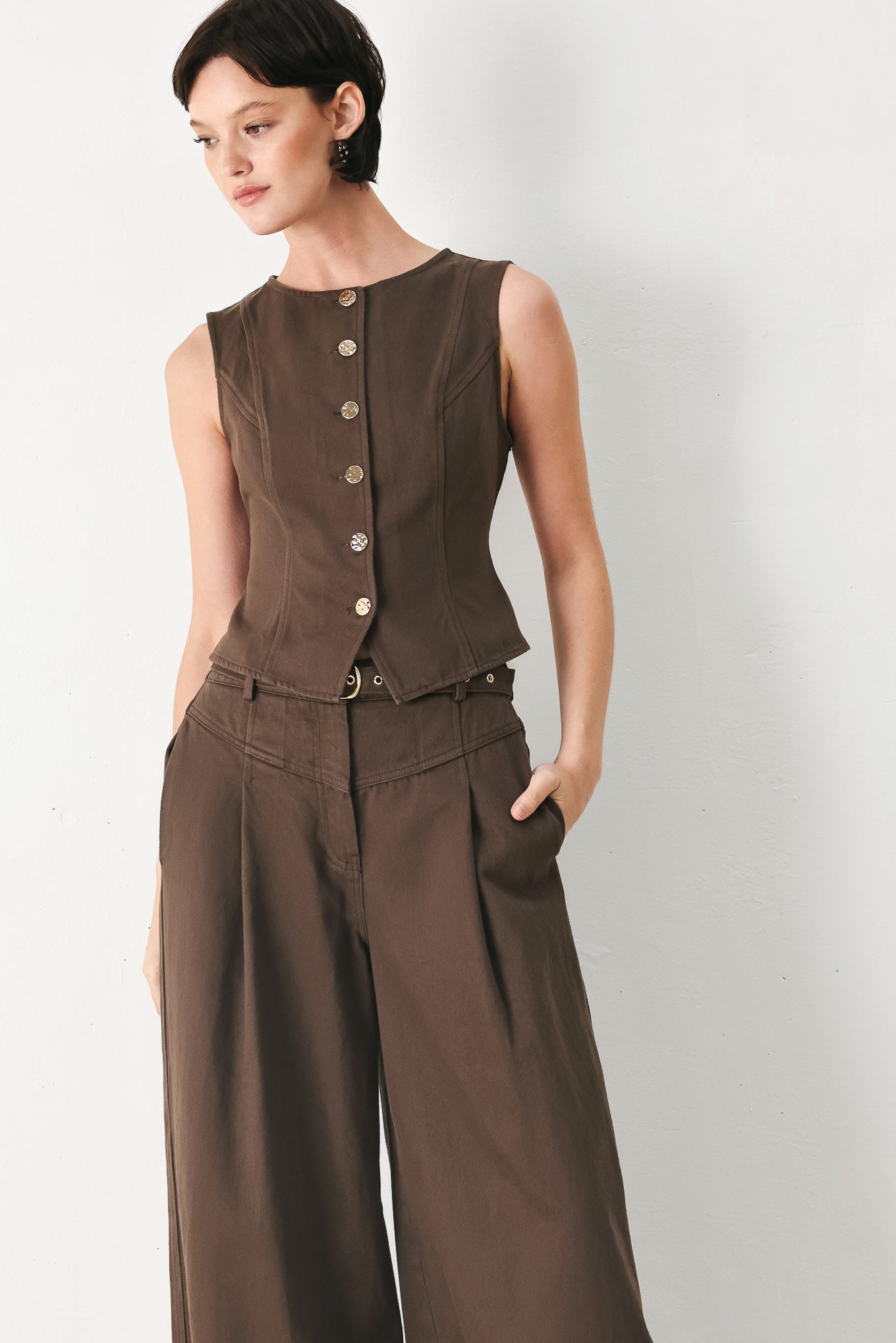 Woman wearing a brown sleeveless vest with round neckline, buttons and matching pants | FREEMARKET 