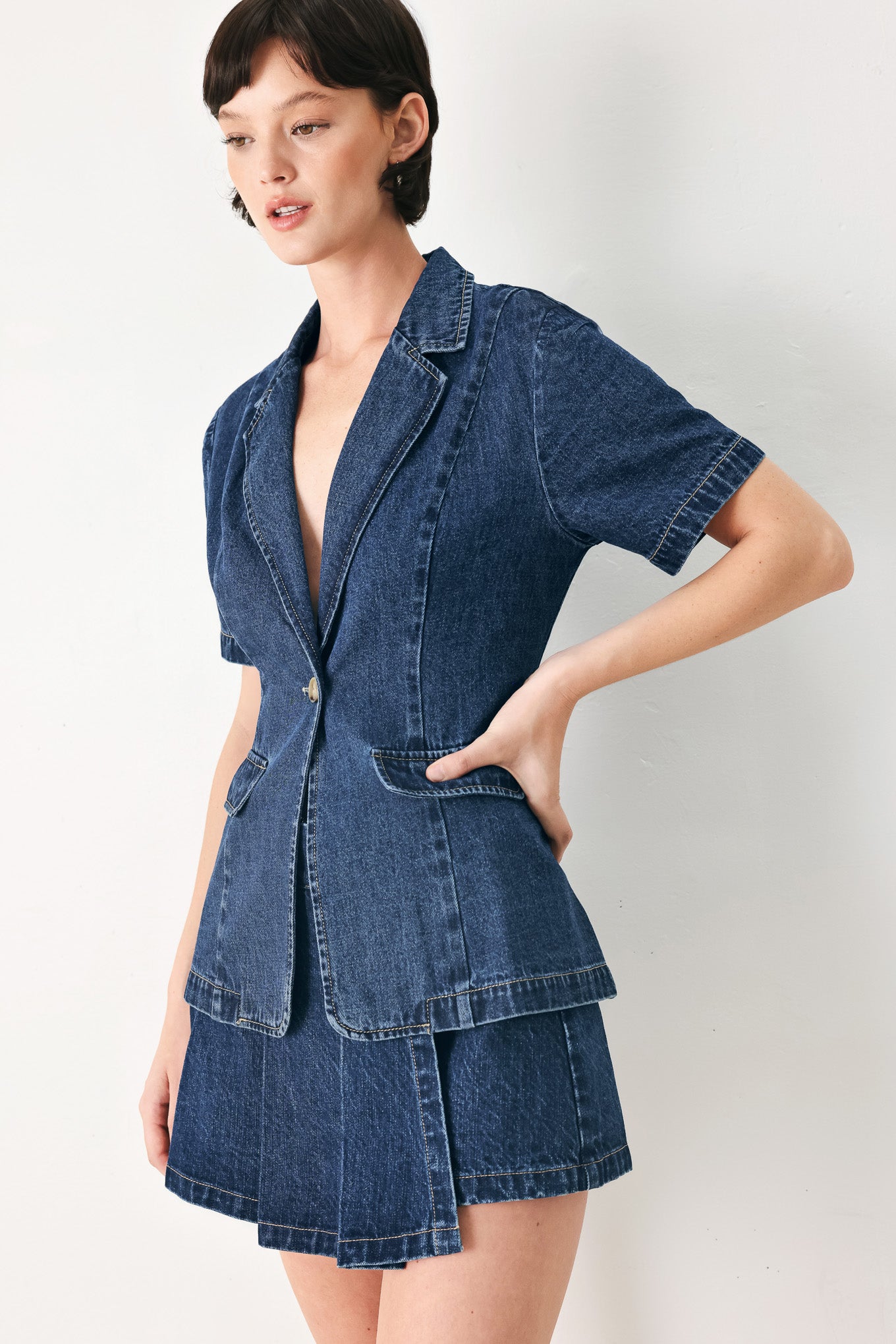Woman wearing a short sleeve washed denim jacket featuring collar, deep v-cut with a single front button closure | FREEMARKET