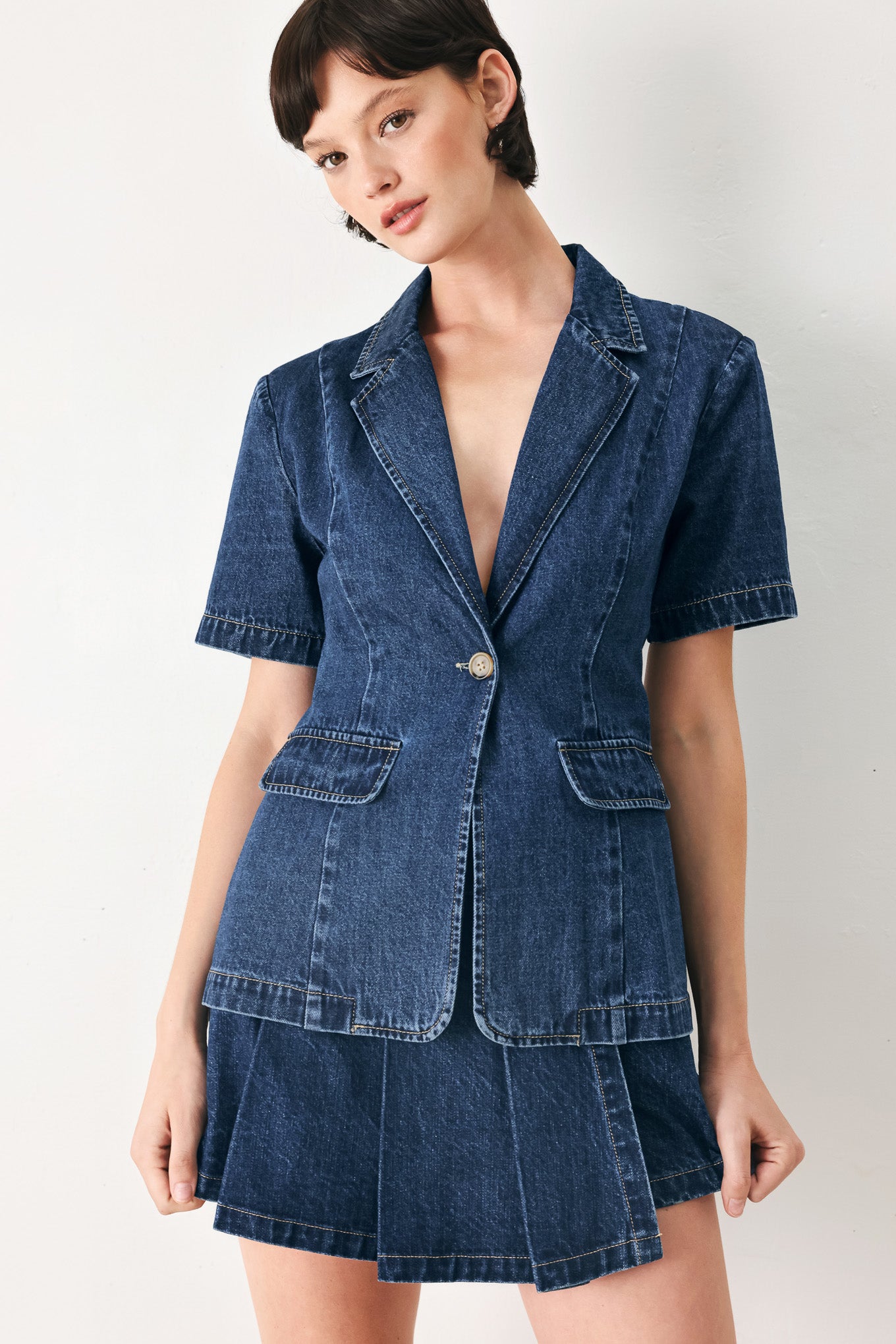 Woman wearing a short sleeve washed denim jacket featuring collar, deep v-cut with a single front button closure | FREEMARKET