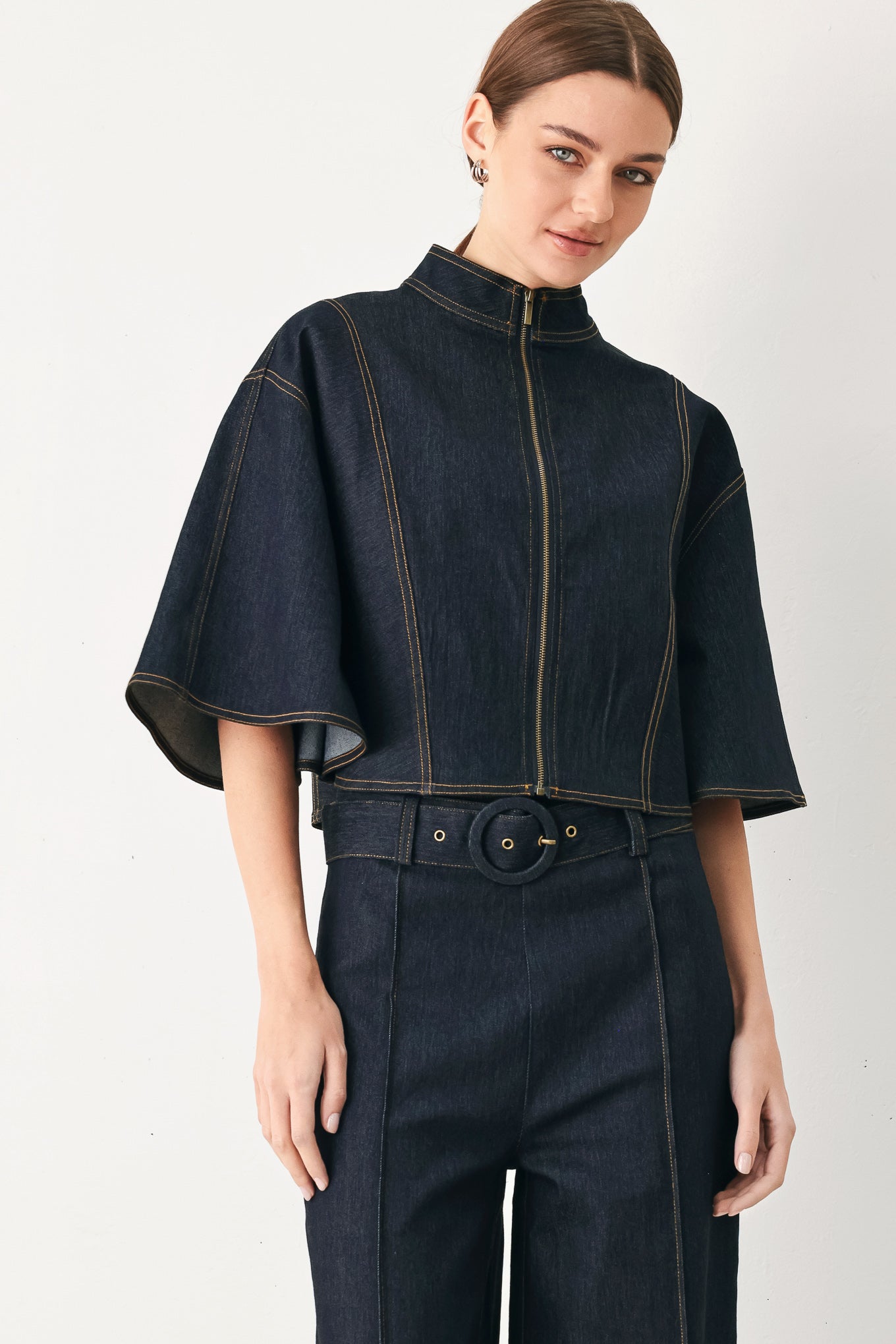 Woman wearing a dark denim capelet top with front zipper closure | FREEMARKET