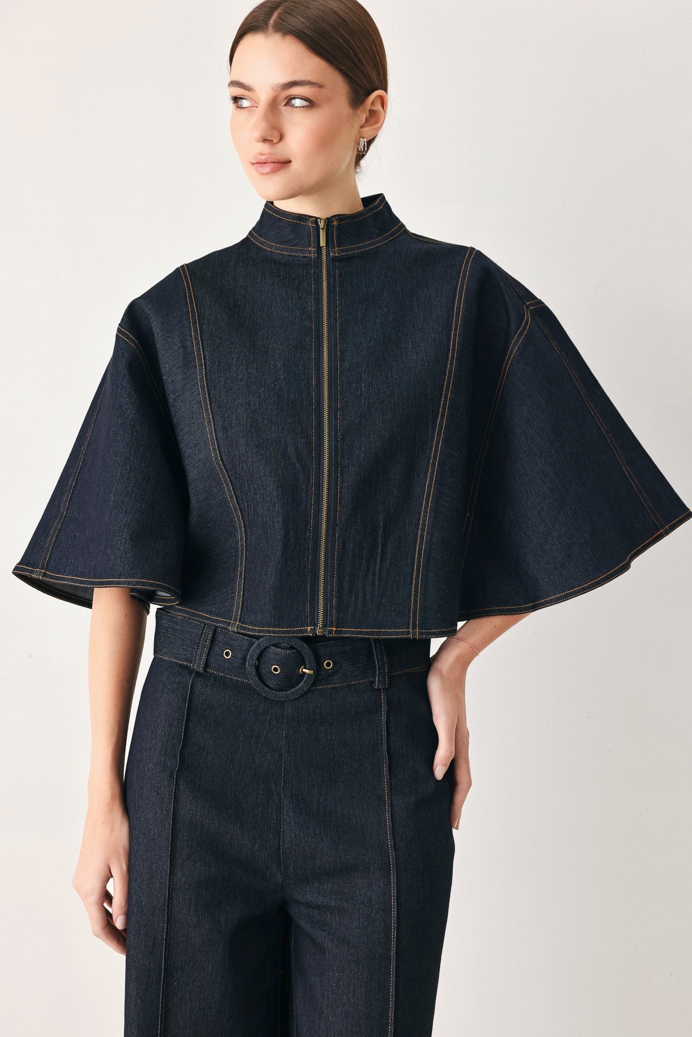 Woman wearing a dark denim capelet top with front zipper closure | FREEMARKET