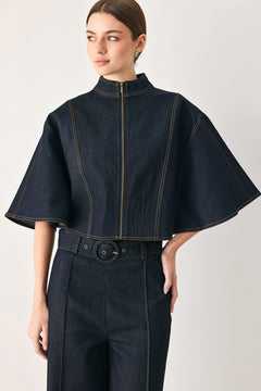Woman wearing a dark denim capelet top with front zipper closure | FREEMARKET