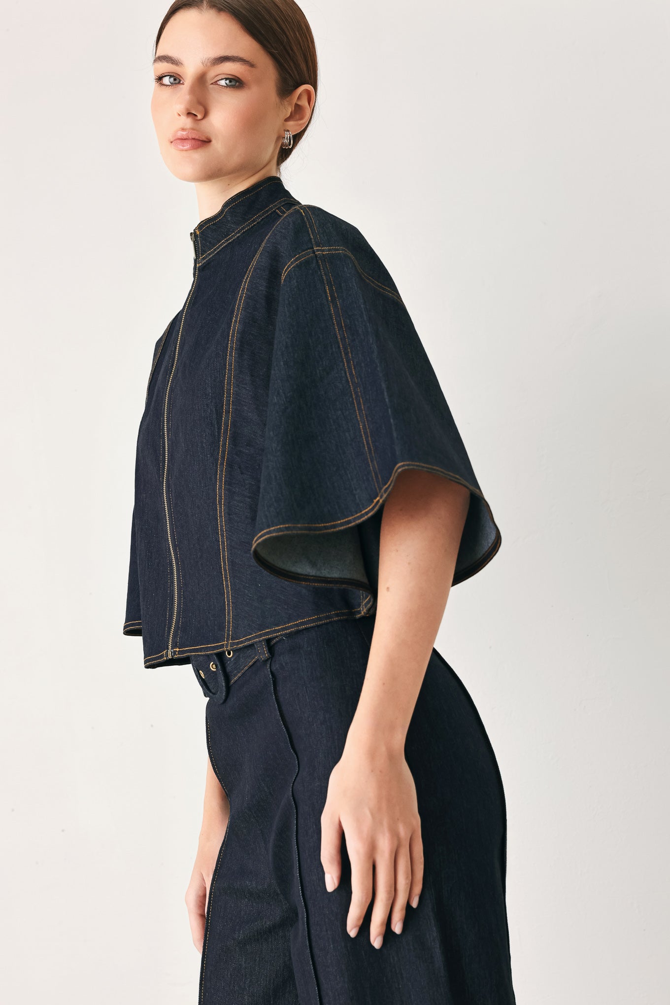 Woman wearing a dark denim capelet top with front zipper closure | FREEMARKET