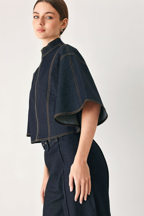 Woman wearing a dark denim capelet top with front zipper closure | FREEMARKET