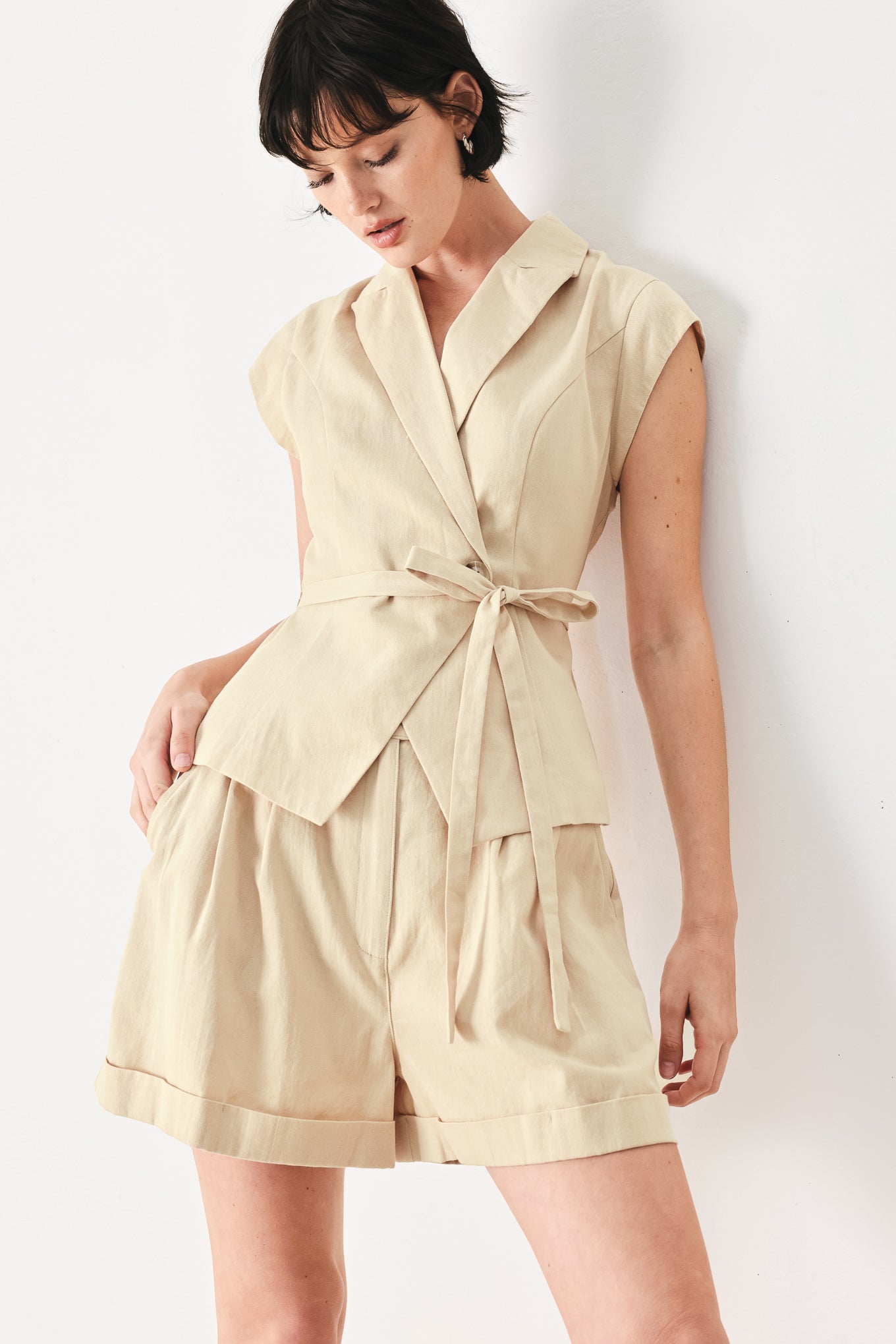 Woman wearing light tan woven vest with collar, cap sleeve and button closure | FREEMARKET