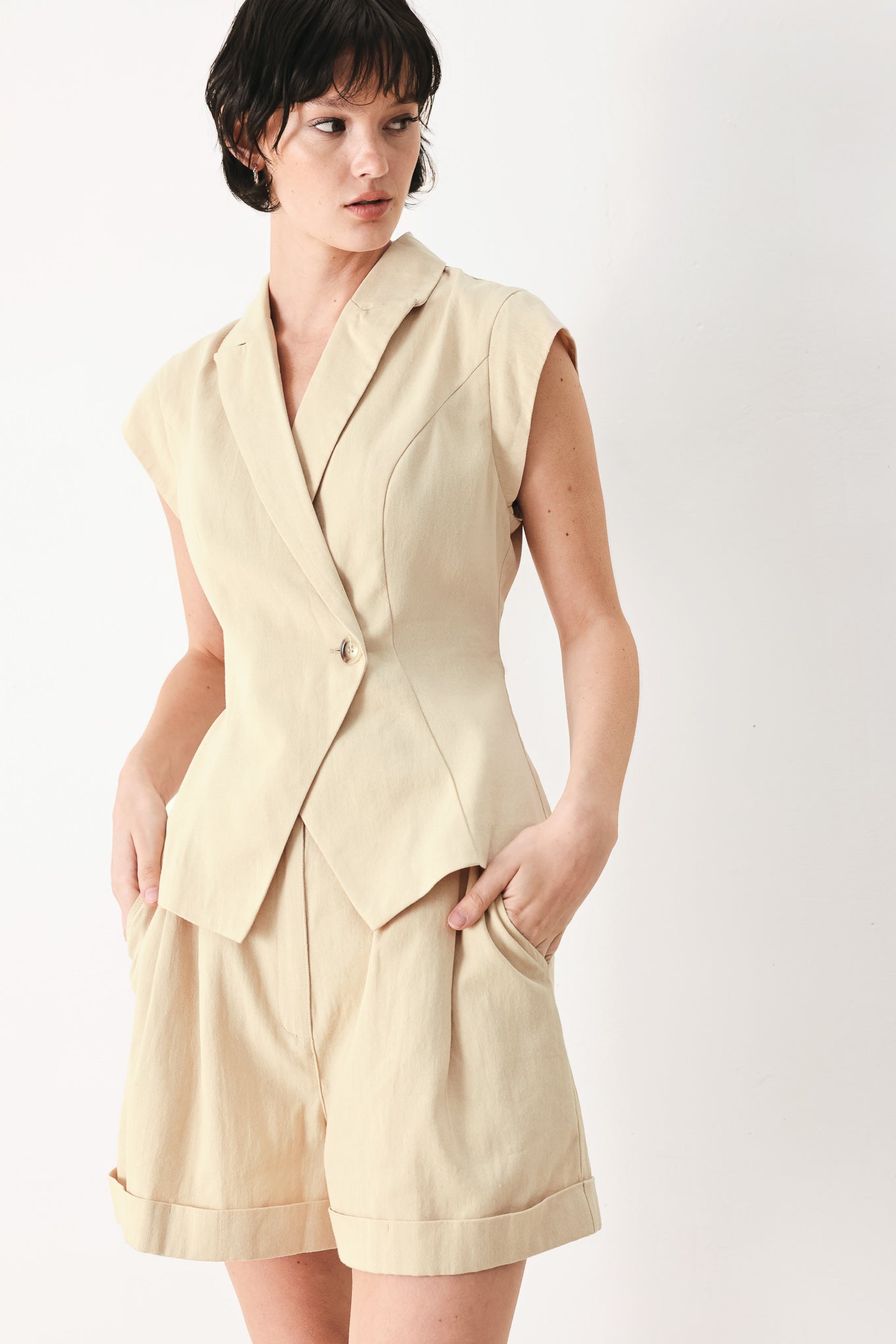 Woman wearing light tan woven vest with collar, cap sleeve and button closure | FREEMARKET